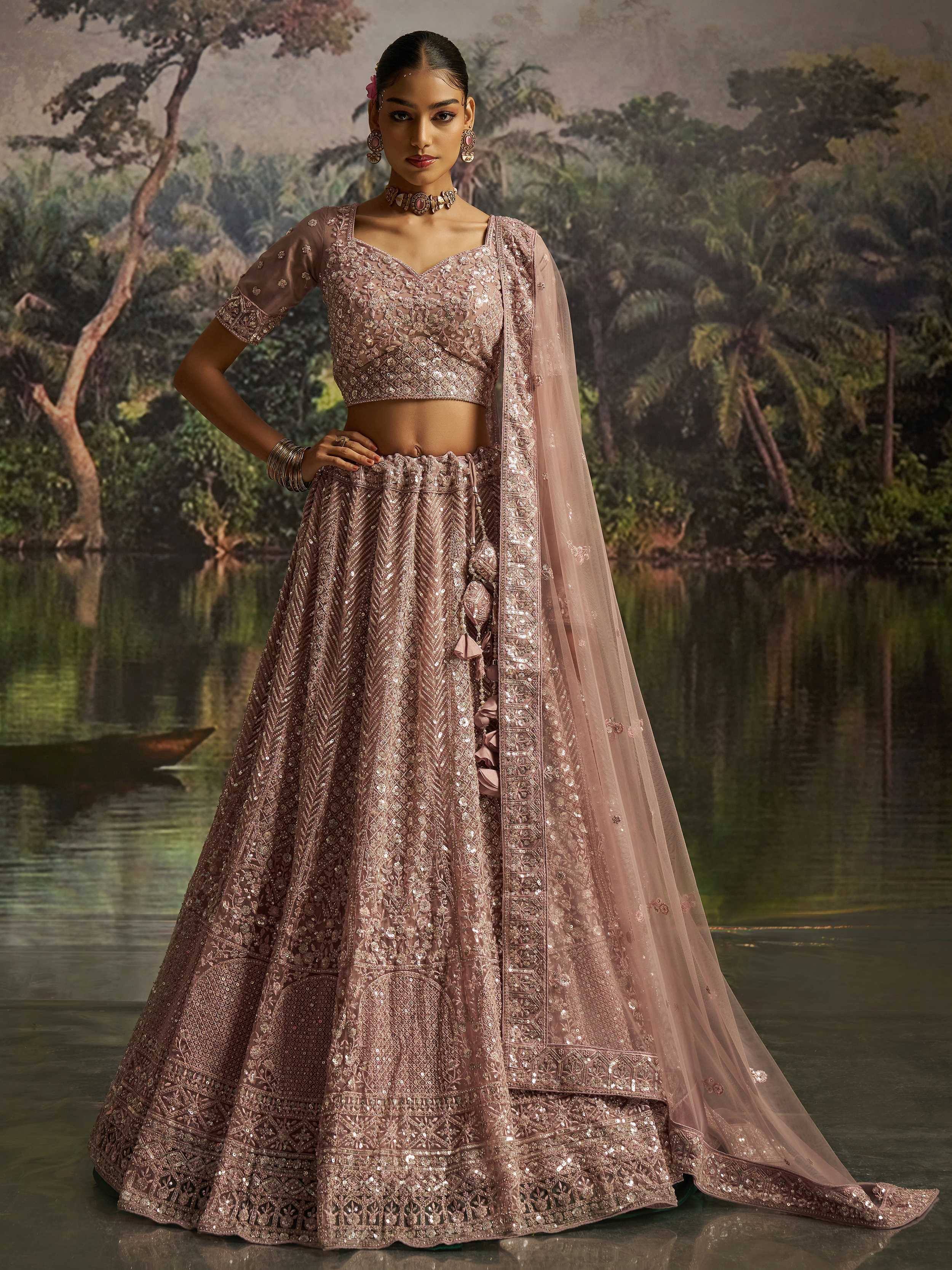 Elegant blush pink designer lehenga choli with intricate embroidery and sequins, perfect for weddings and festive occasions.