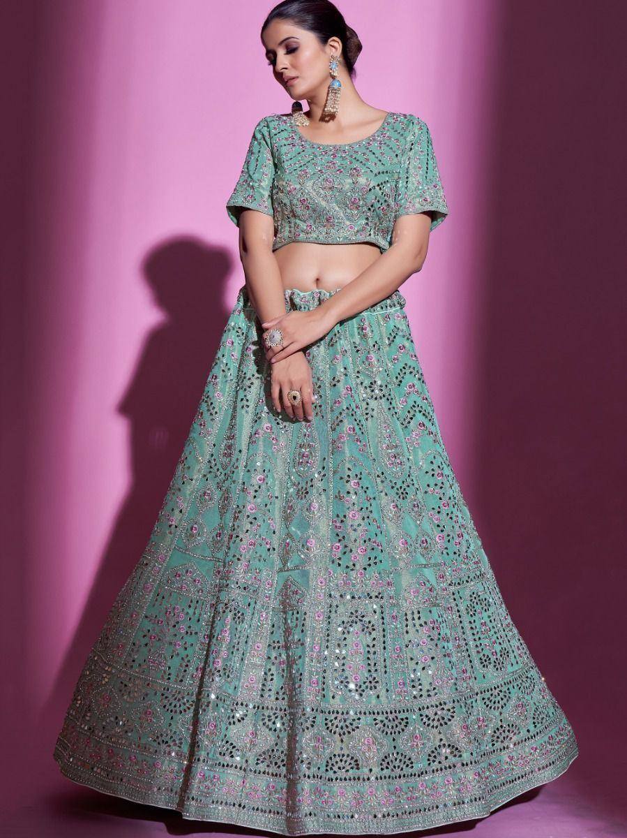 Mint green designer lehenga choli with intricate embroidery and mirror work, perfect for Indian ethnic wear.