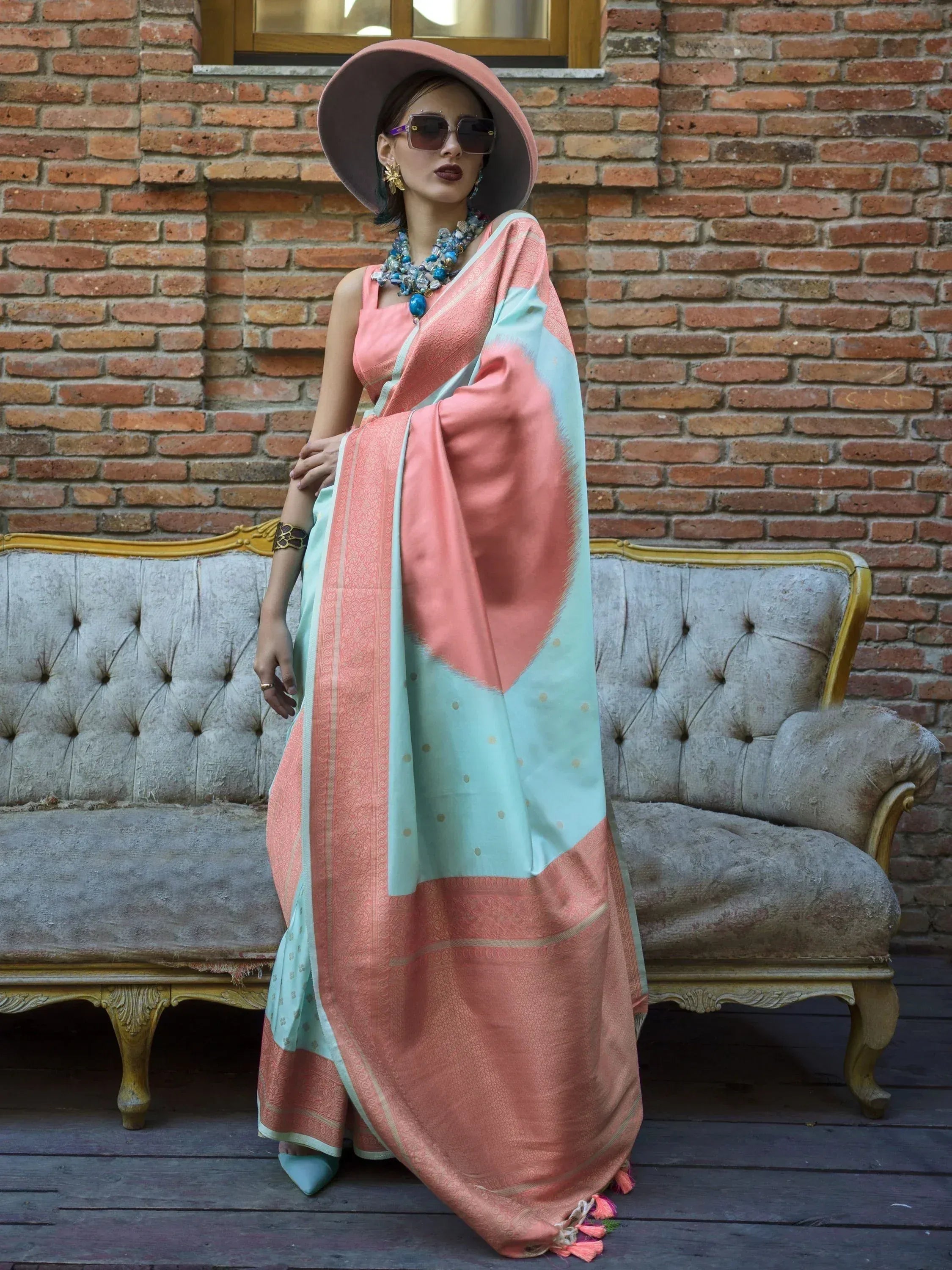 Woman in coral and mint designer saree with wide brim hat, styled for ethnic fashion