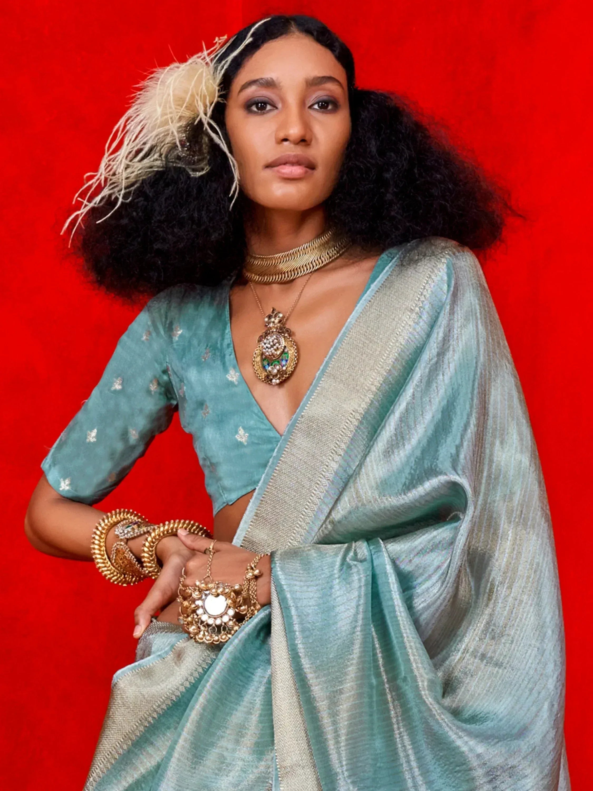 Woman in teal designer saree with gold jewelry, ethnic wear for festive occasions