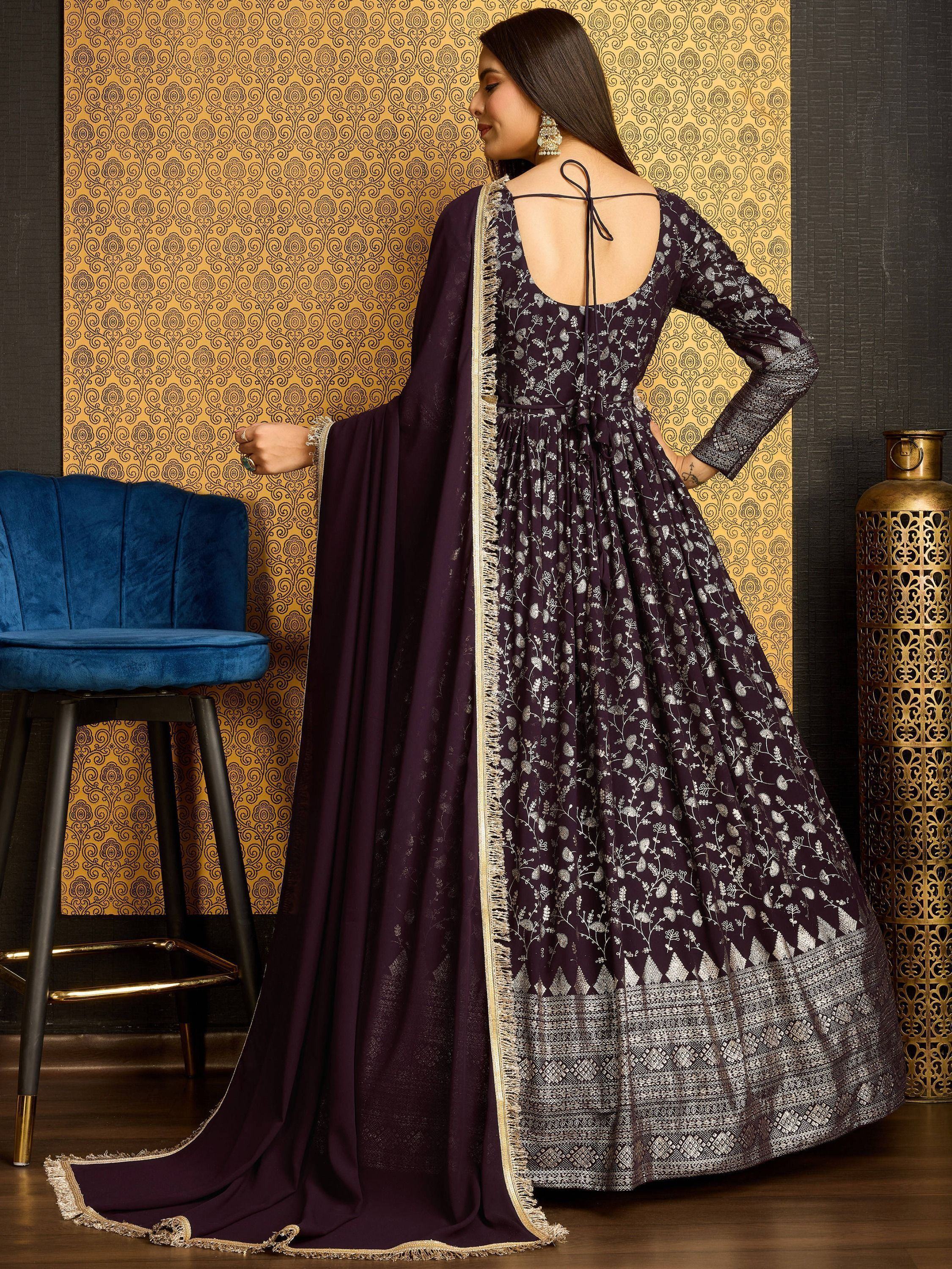 Woman in purple embroidered ethnic gown with dupatta, back pose, traditional decor
