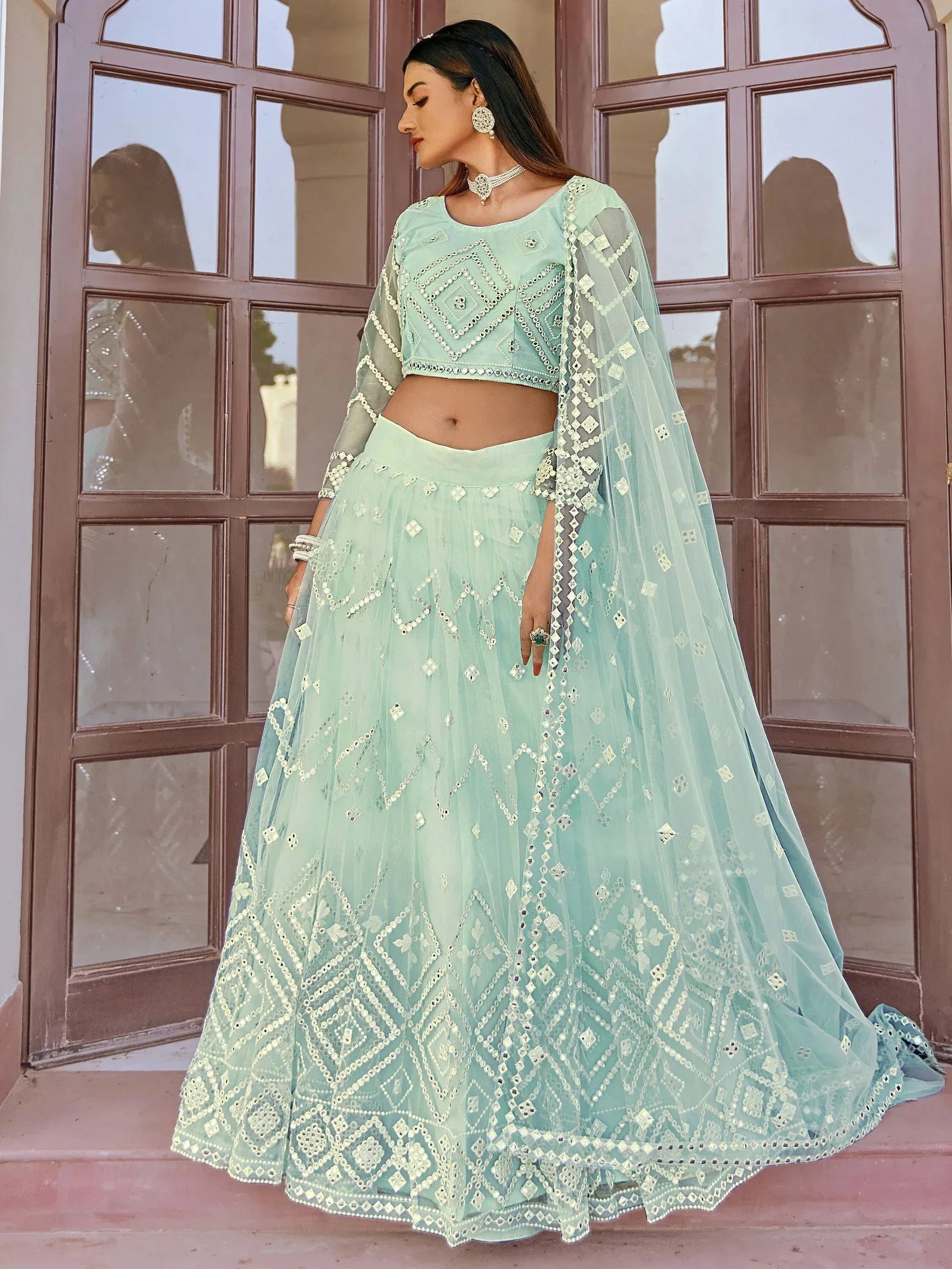 Mint green designer lehenga choli with mirror work and sheer dupatta, perfect for Indian ethnic wear occasions.