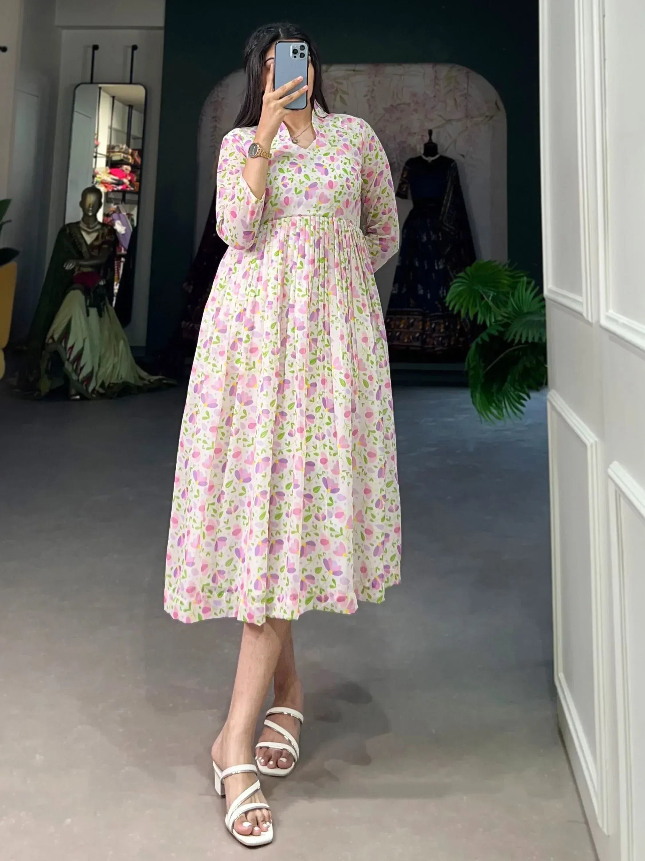 Woman in floral print ethnic gown with long sleeves, mirror selfie in boutique