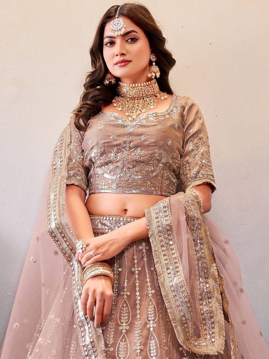 Elegant beige embroidered lehenga choli with heavy jewelry, perfect for Indian weddings and festive occasions.