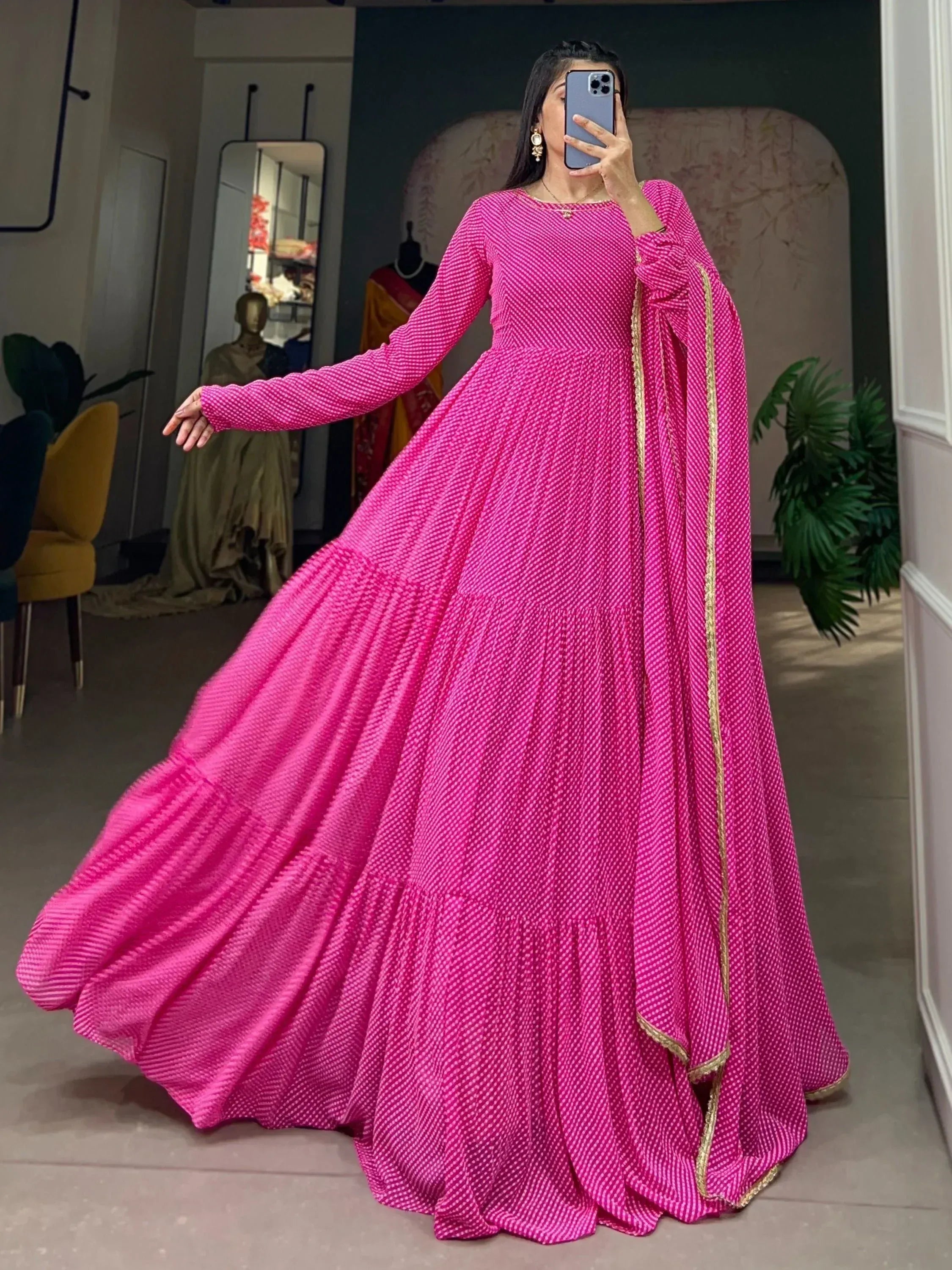 Vibrant pink ethnic gown with gold trim, long sleeves, and flared skirt for festive occasions