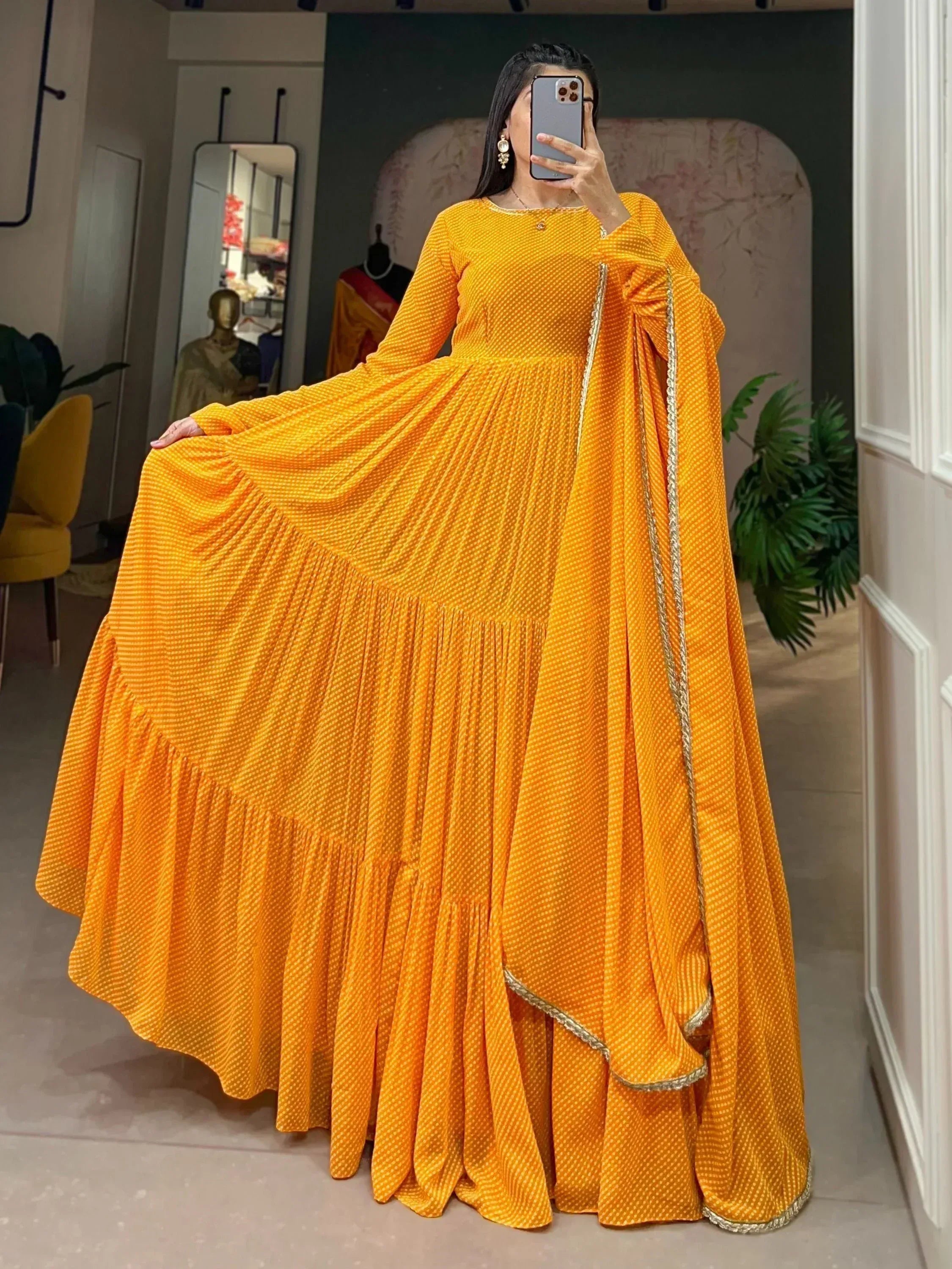 Vibrant yellow ethnic gown with gold trim, pleated skirt, and long sleeves for festive occasions