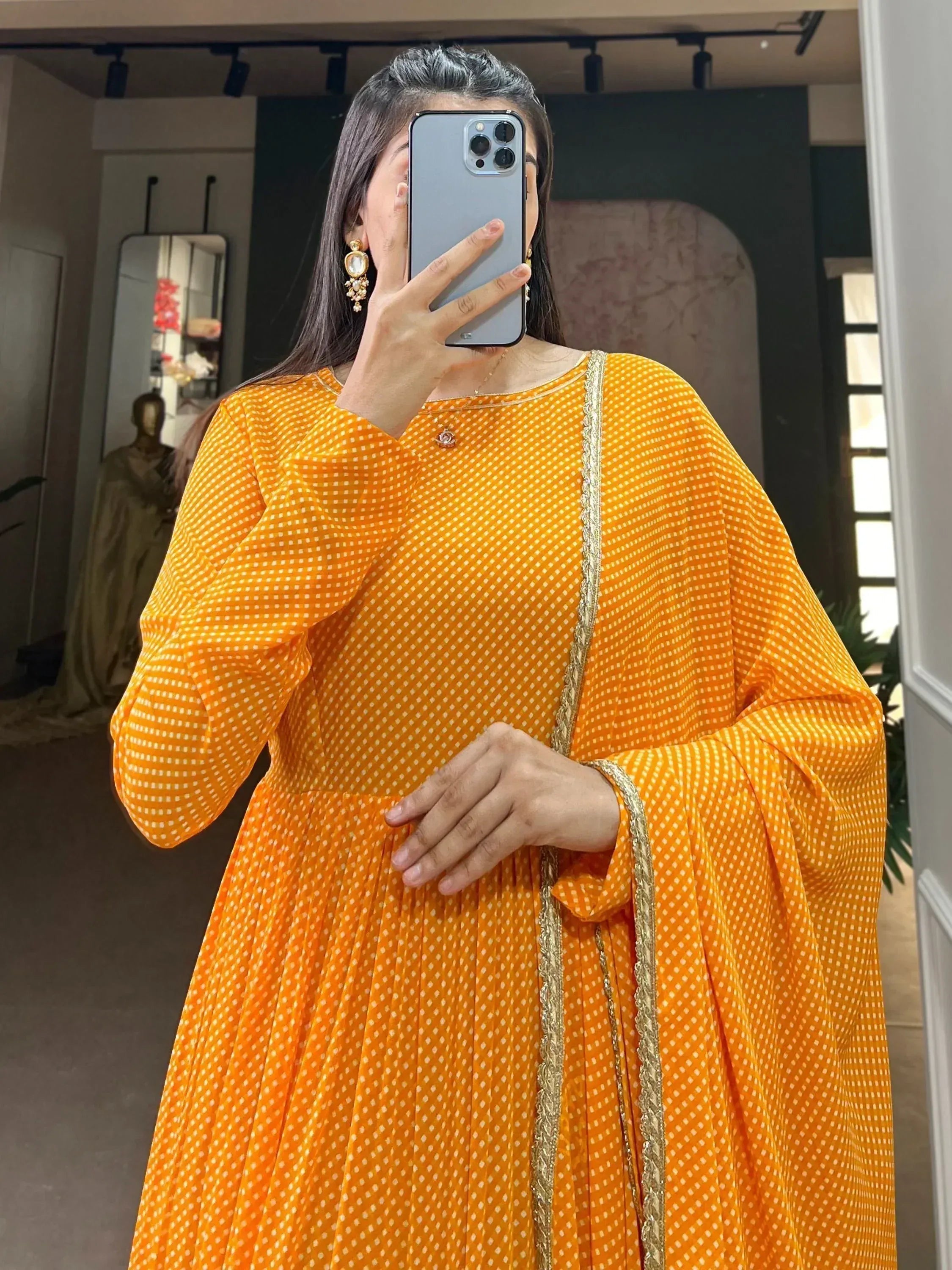 Vibrant orange ethnic gown with white polka dots and gold trim, perfect for festive occasions.