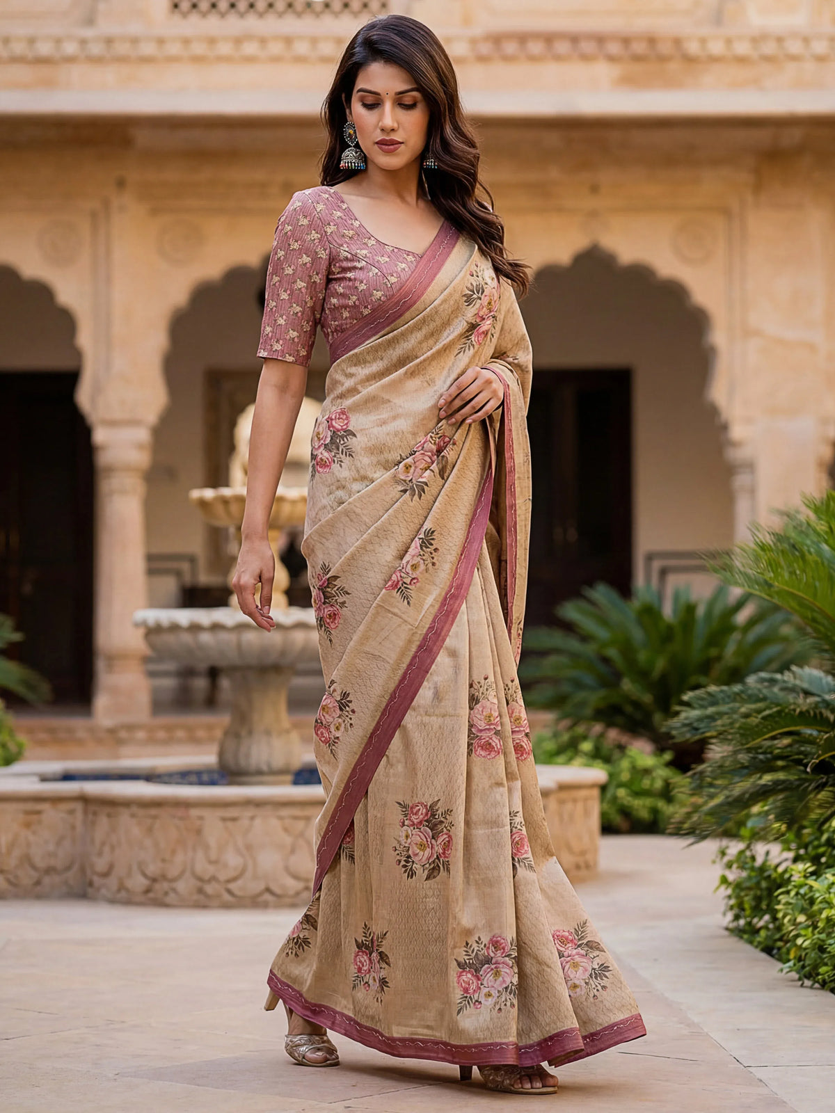 Woman wearing a beige floral print saree with a mauve blouse in a traditional Indian courtyard