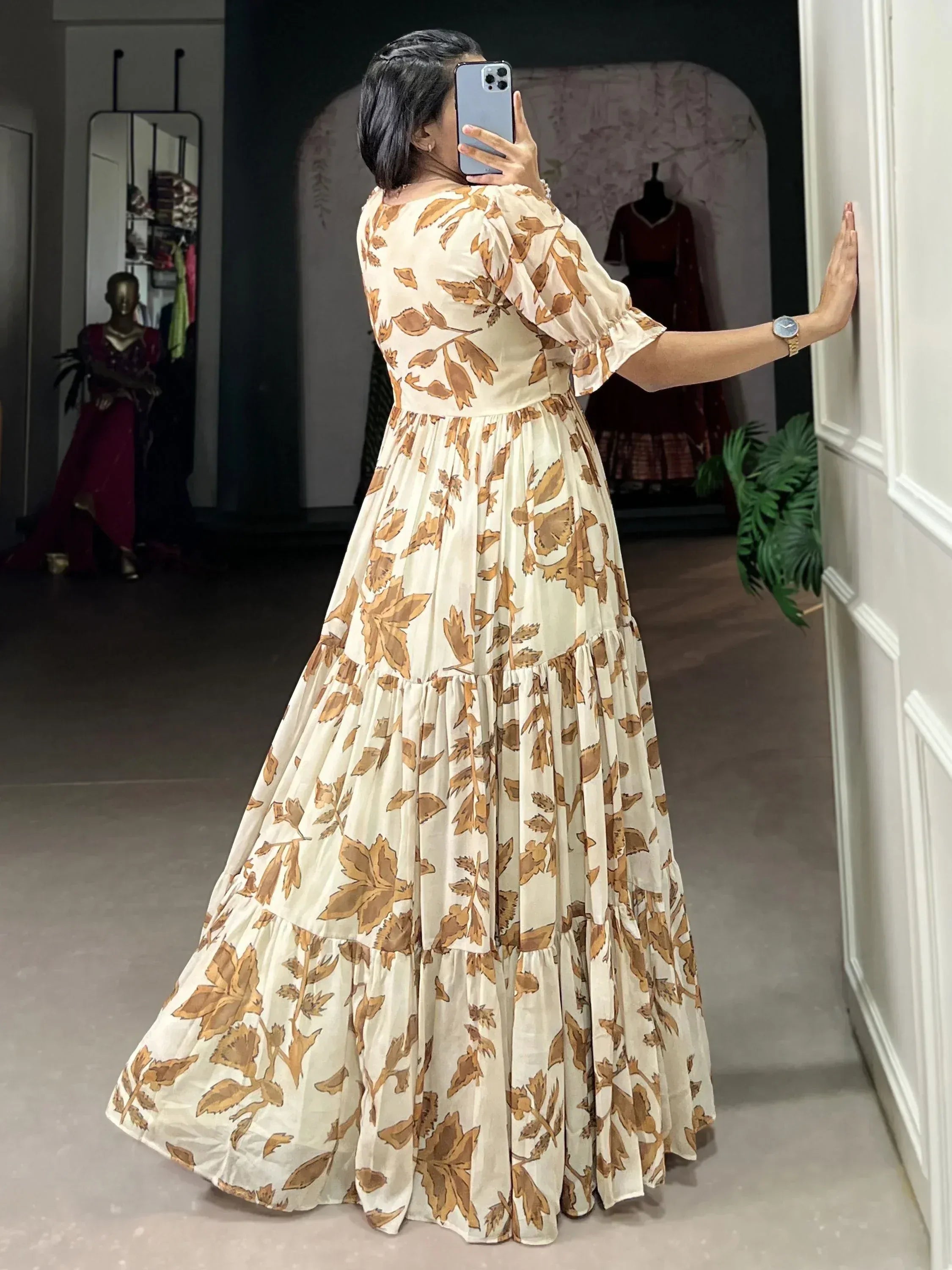 Woman in cream and brown floral printed ethnic gown posing indoors, back view