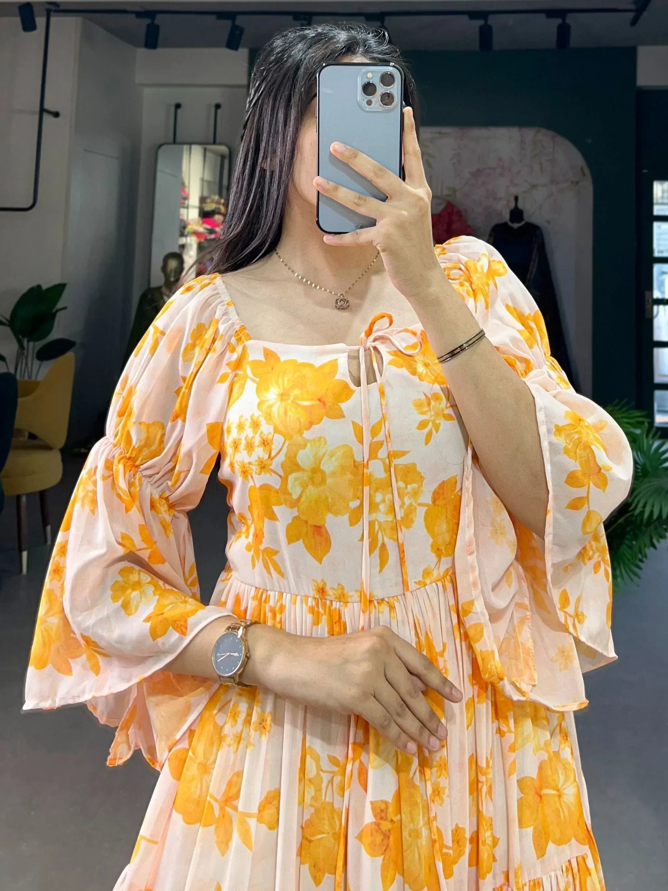 Woman wearing a yellow floral ethnic gown with flared sleeves, taking a mirror selfie