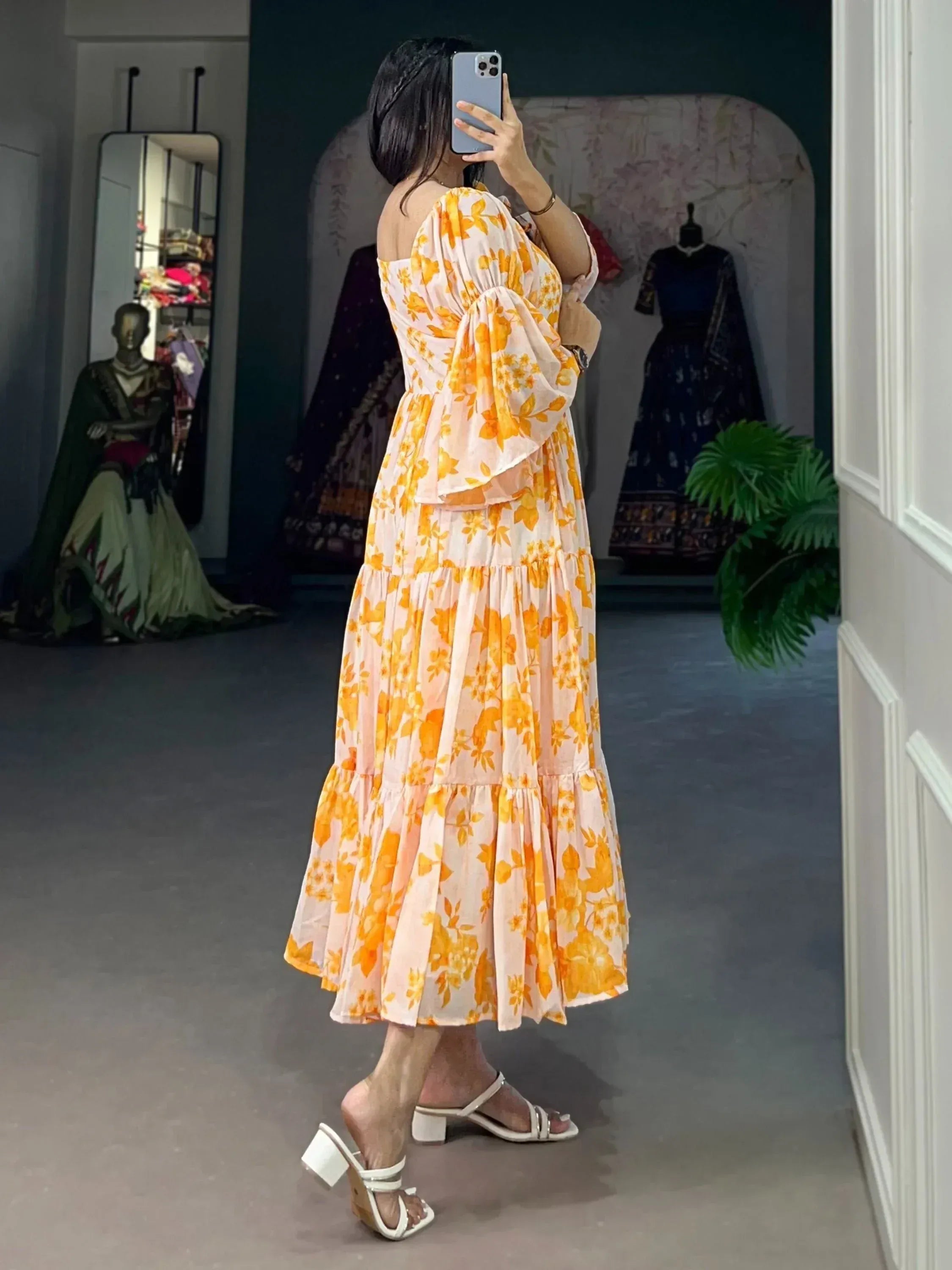 Woman in a flowy yellow floral midi dress with bell sleeves, side view, indoor setting