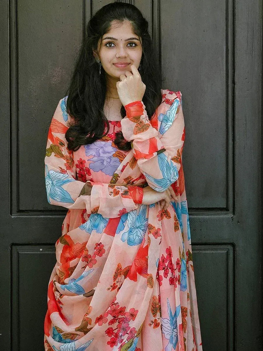 Woman in floral printed ethnic gown with ruffled sleeves, standing against dark door