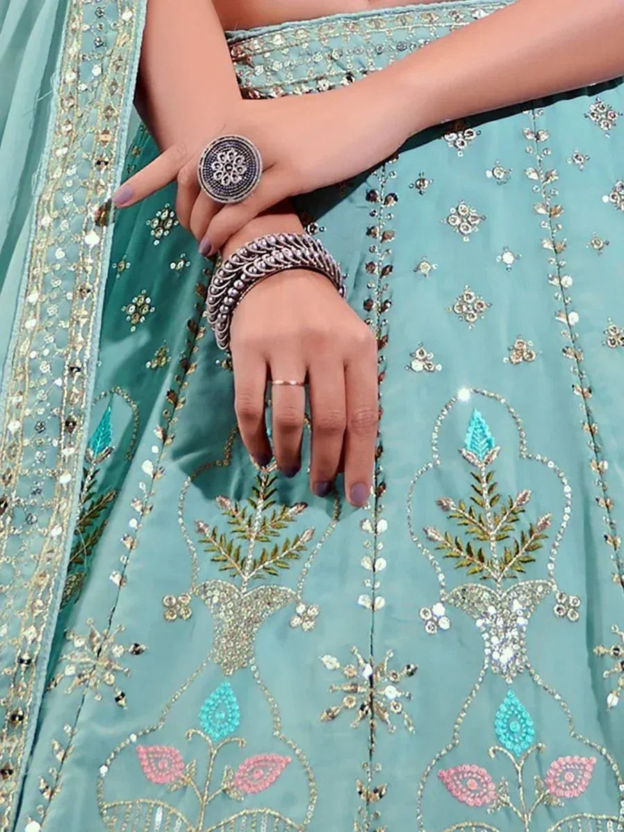 Teal embroidered lehenga choli with floral motifs, paired with statement silver jewelry for ethnic wear.