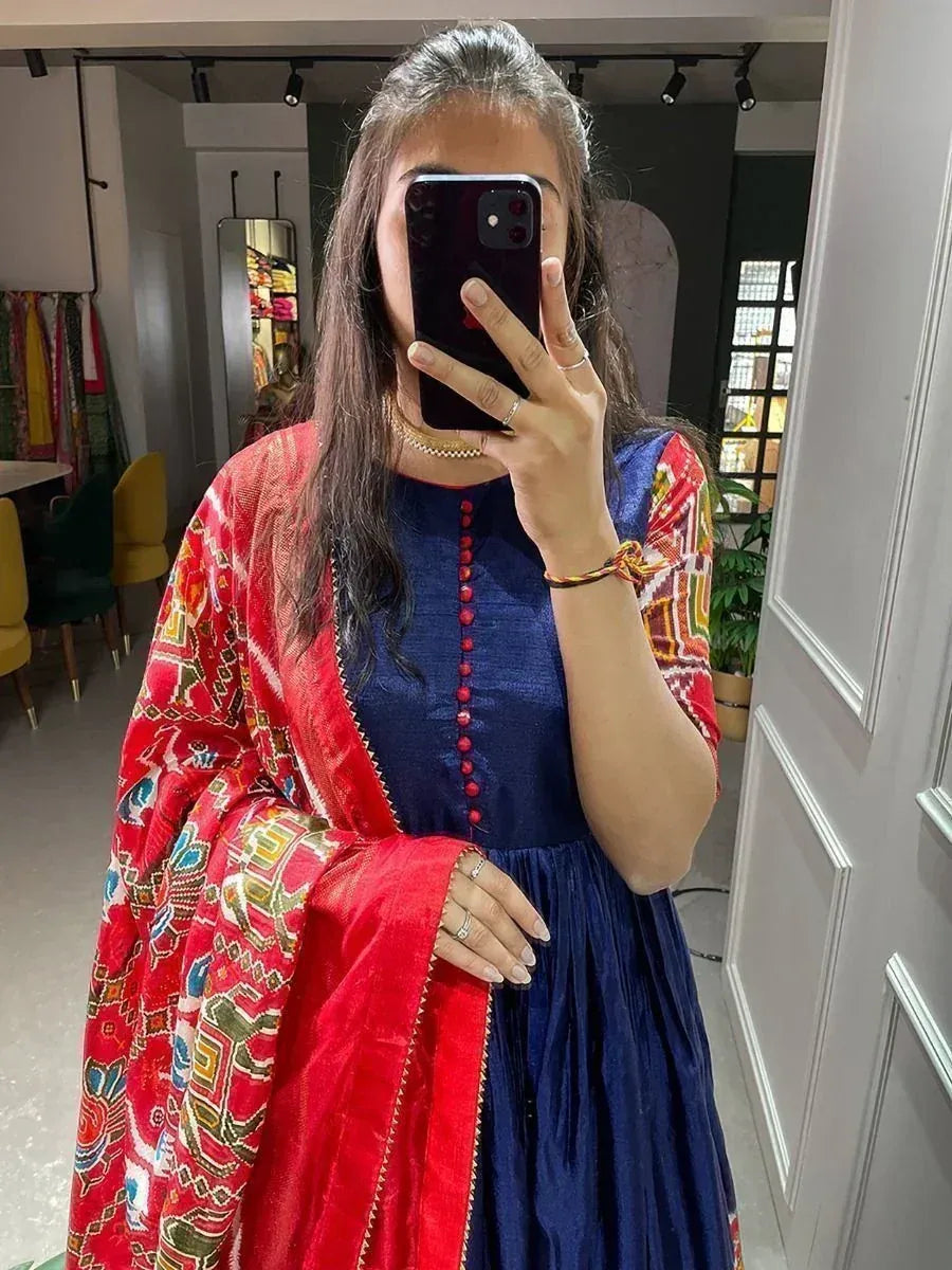 Woman in blue ethnic gown with red printed dupatta, taking mirror selfie in boutique