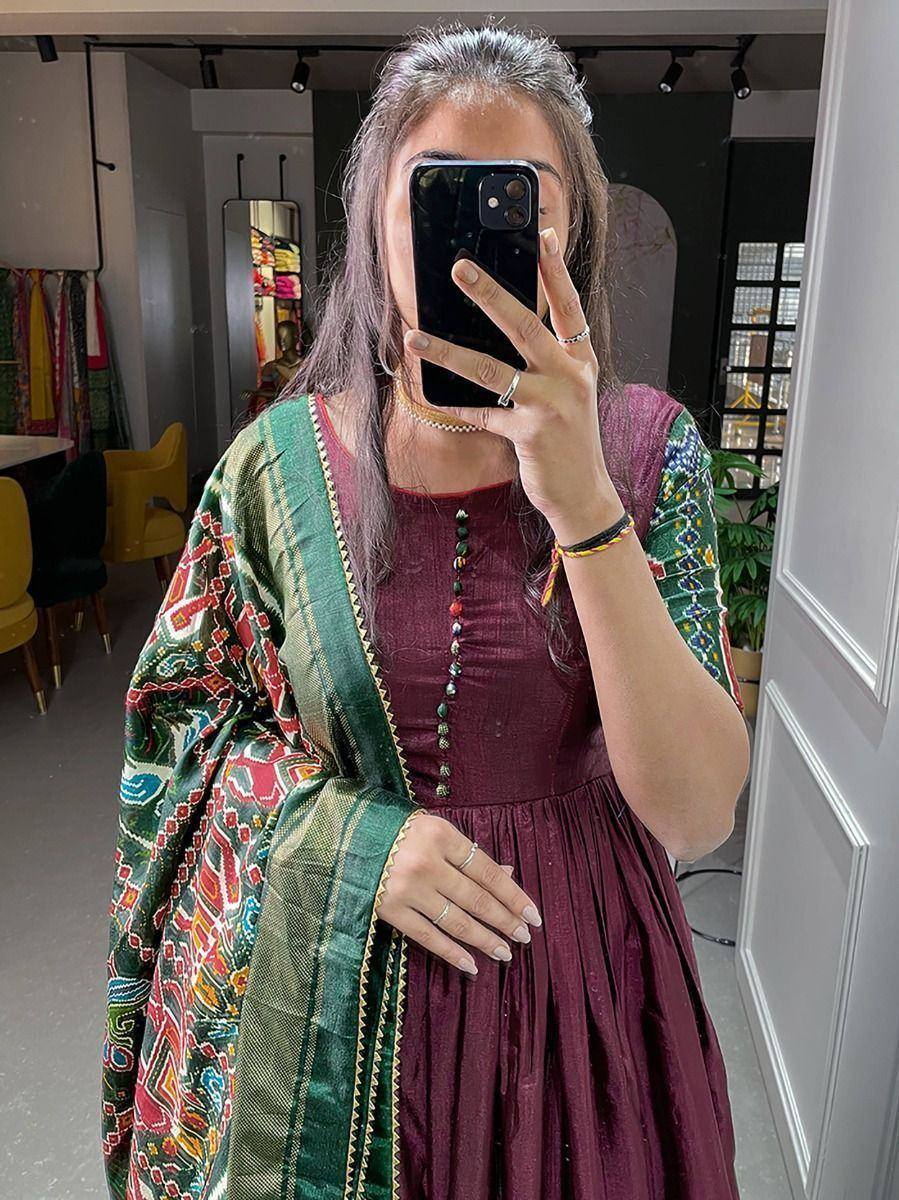 Woman in maroon ethnic gown with colorful printed dupatta, taking mirror selfie in boutique