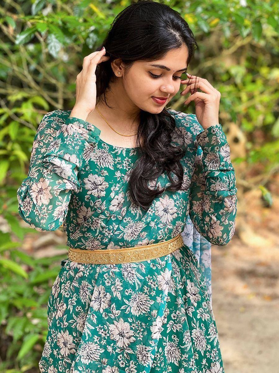 Woman in green floral ethnic gown with gold belt, perfect for Indian occasions