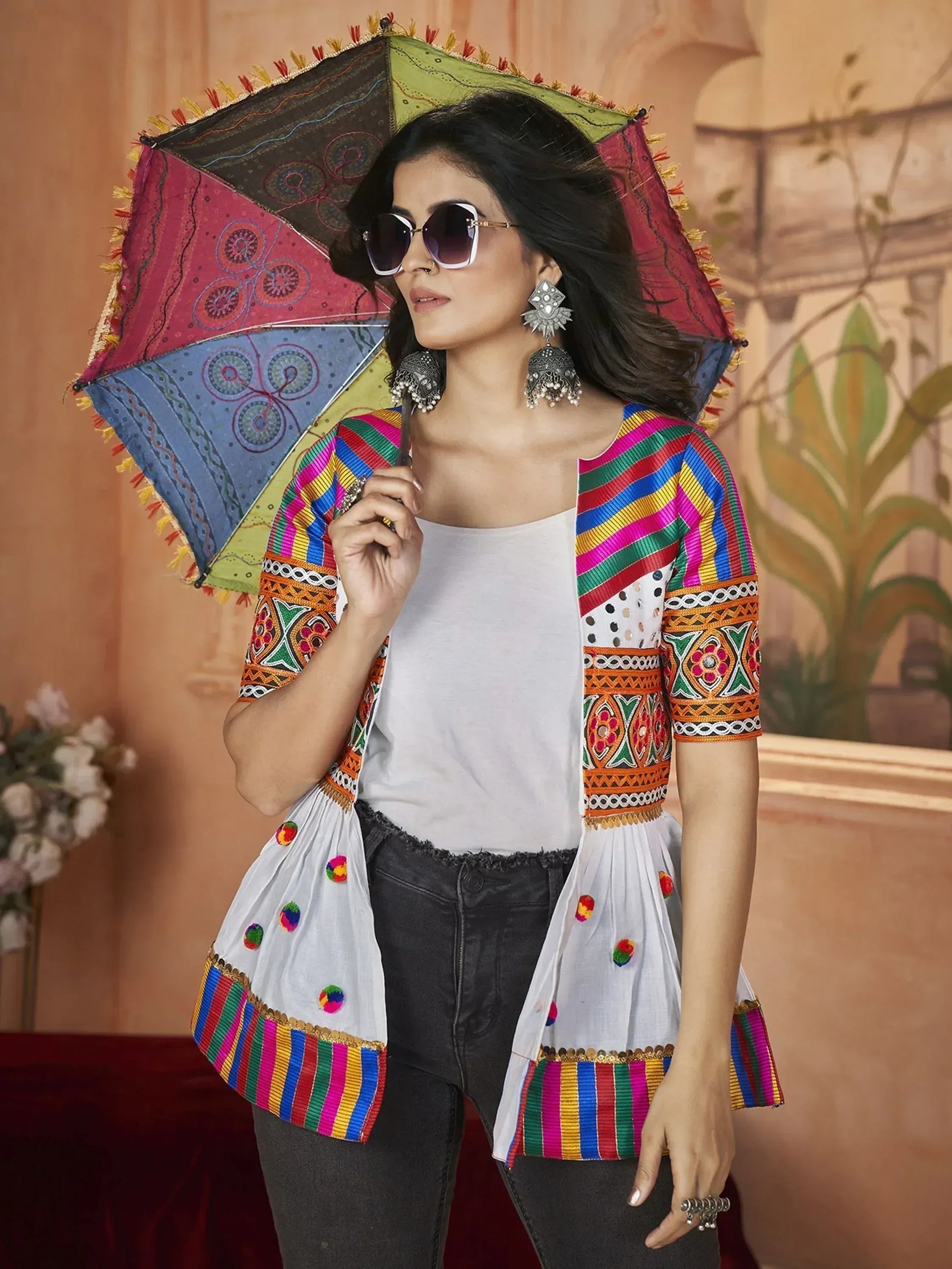 Woman in ethnic embroidered shrug and statement earrings holding colorful umbrella