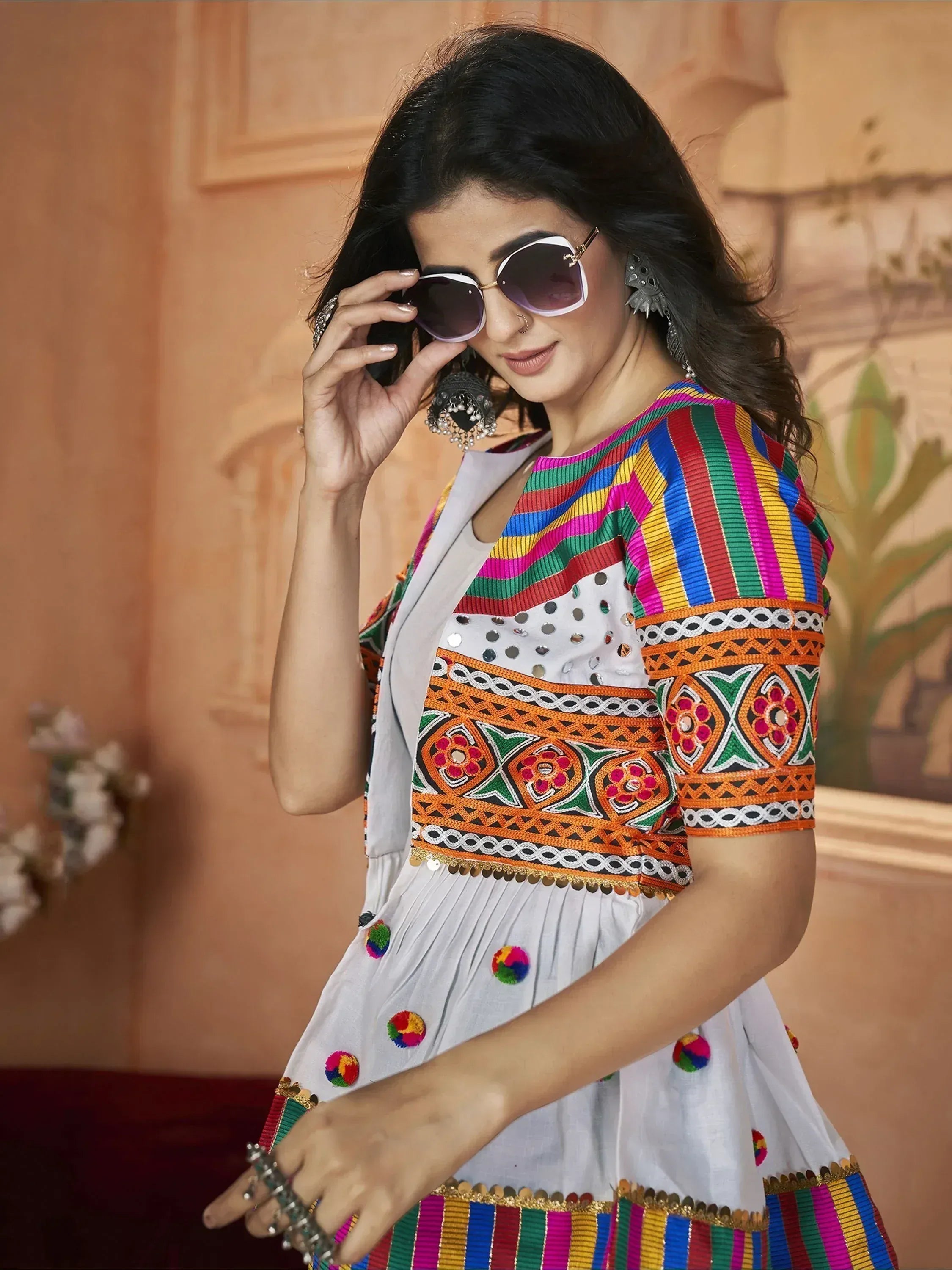 Woman in vibrant multicolor embroidered ethnic gown with sunglasses and statement earrings