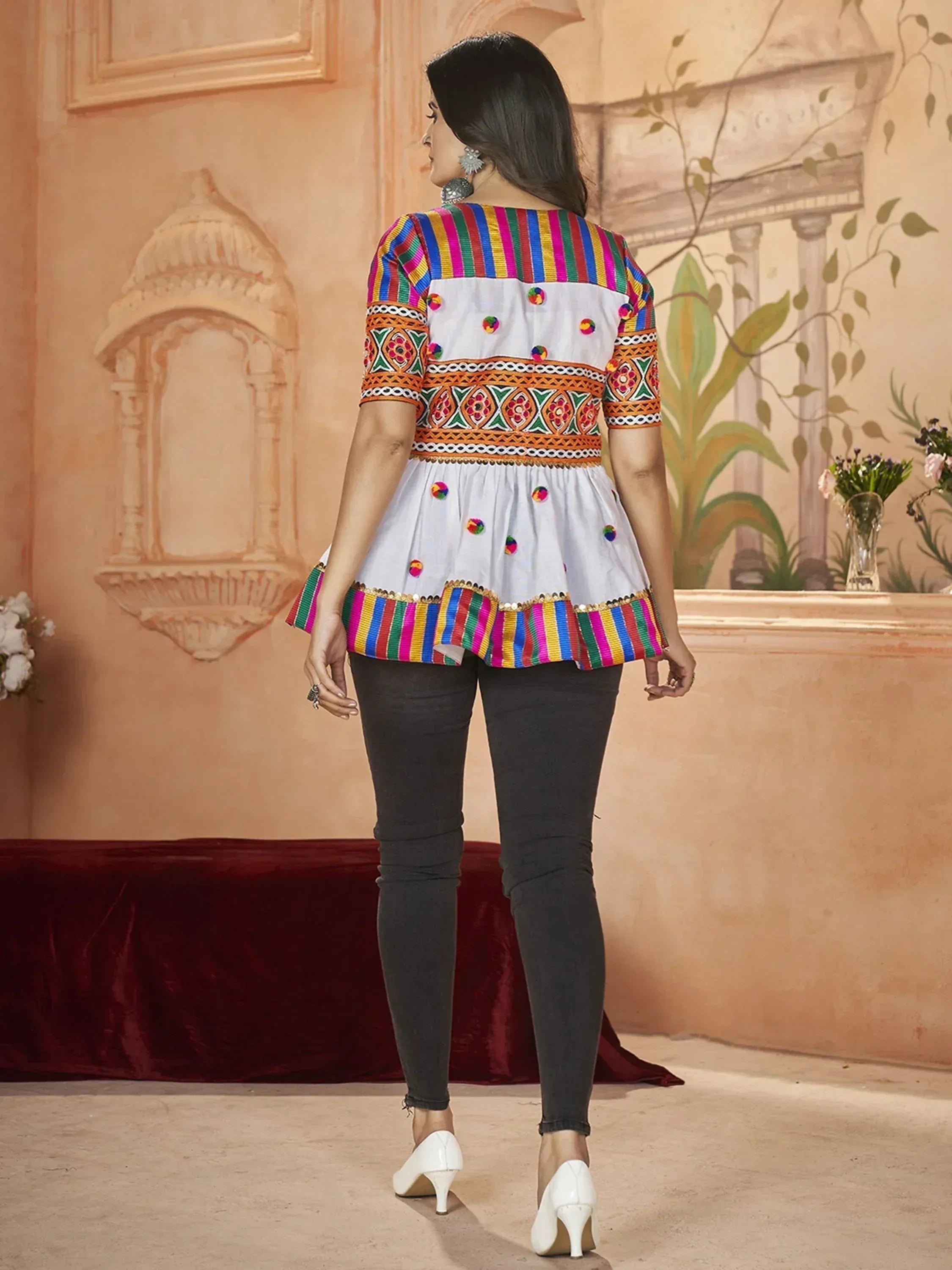 Woman in colorful embroidered peplum top and black jeans, Indian ethnic wear, indoor setting
