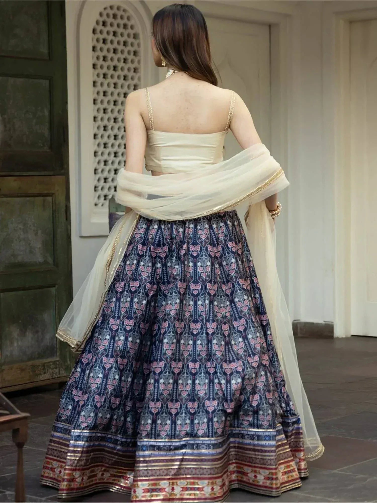Back view of woman in navy floral lehenga choli with gold trim, cream dupatta, ethnic Indian wear