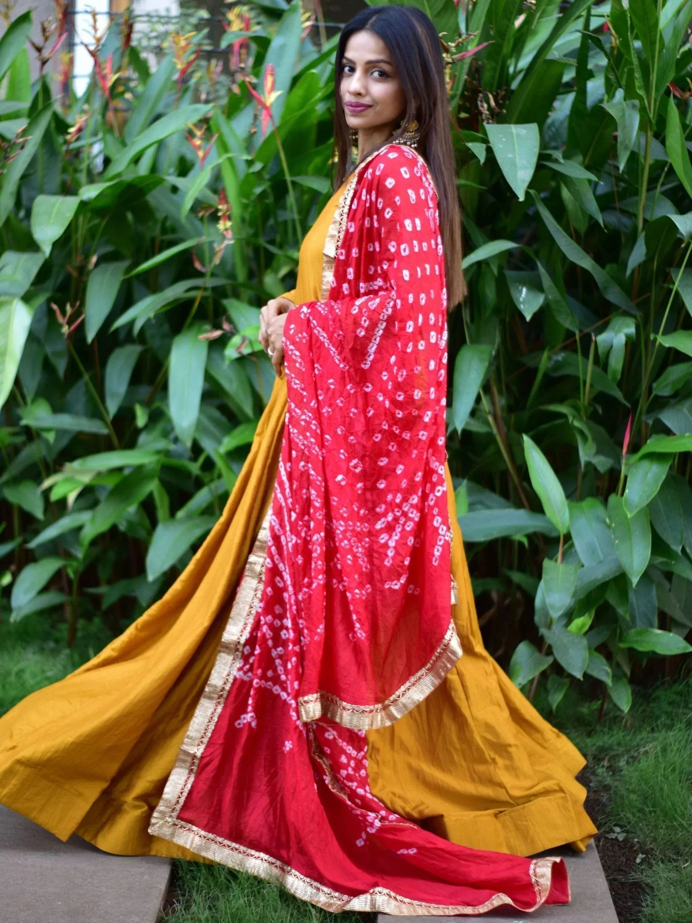 Woman in red bandhani dupatta with mustard yellow lehenga, ethnic Indian wear for festive occasions