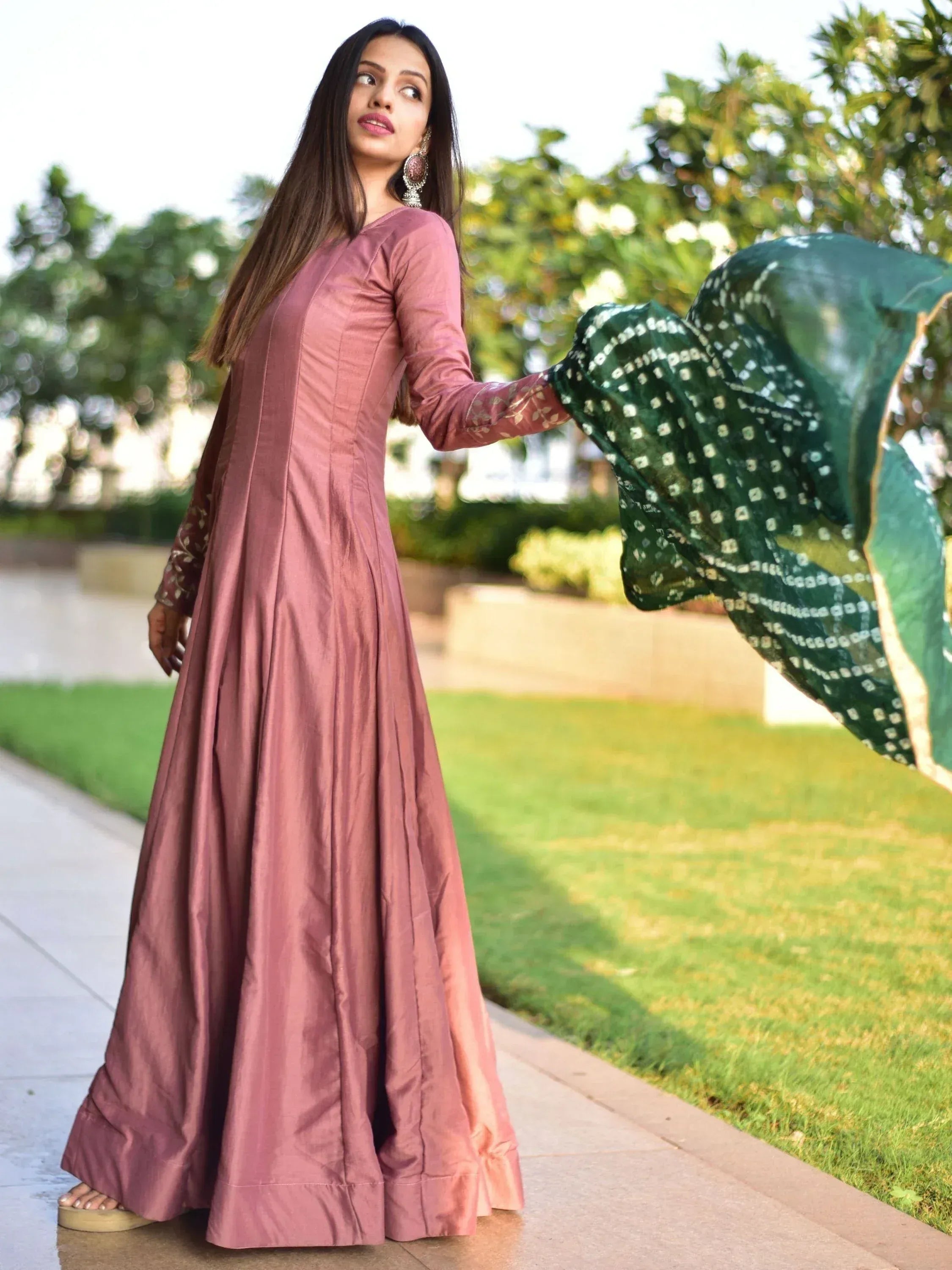 Woman in dusty rose ethnic gown with green printed dupatta, outdoor garden setting