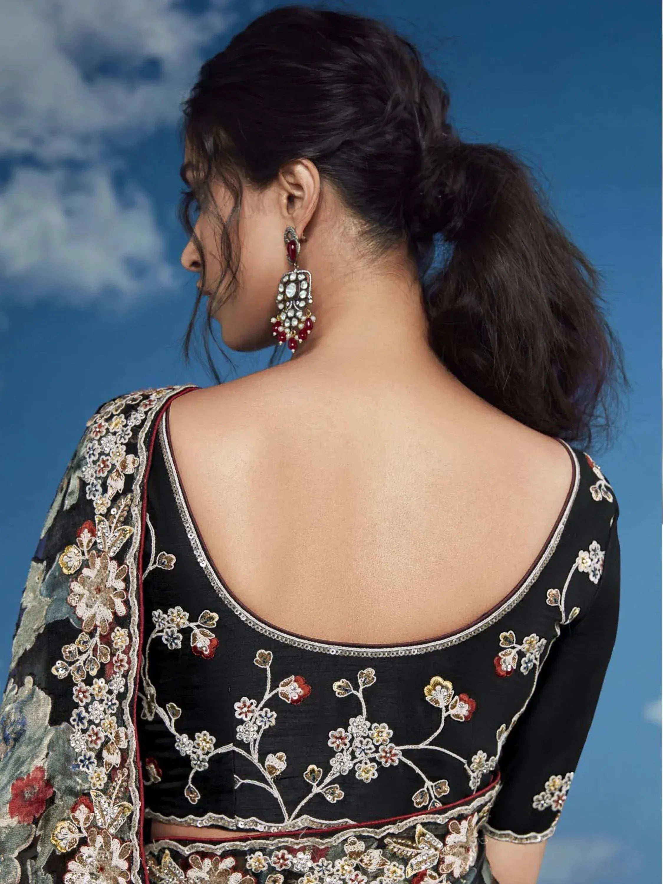 Black floral embroidered lehenga choli with deep back design and traditional earrings