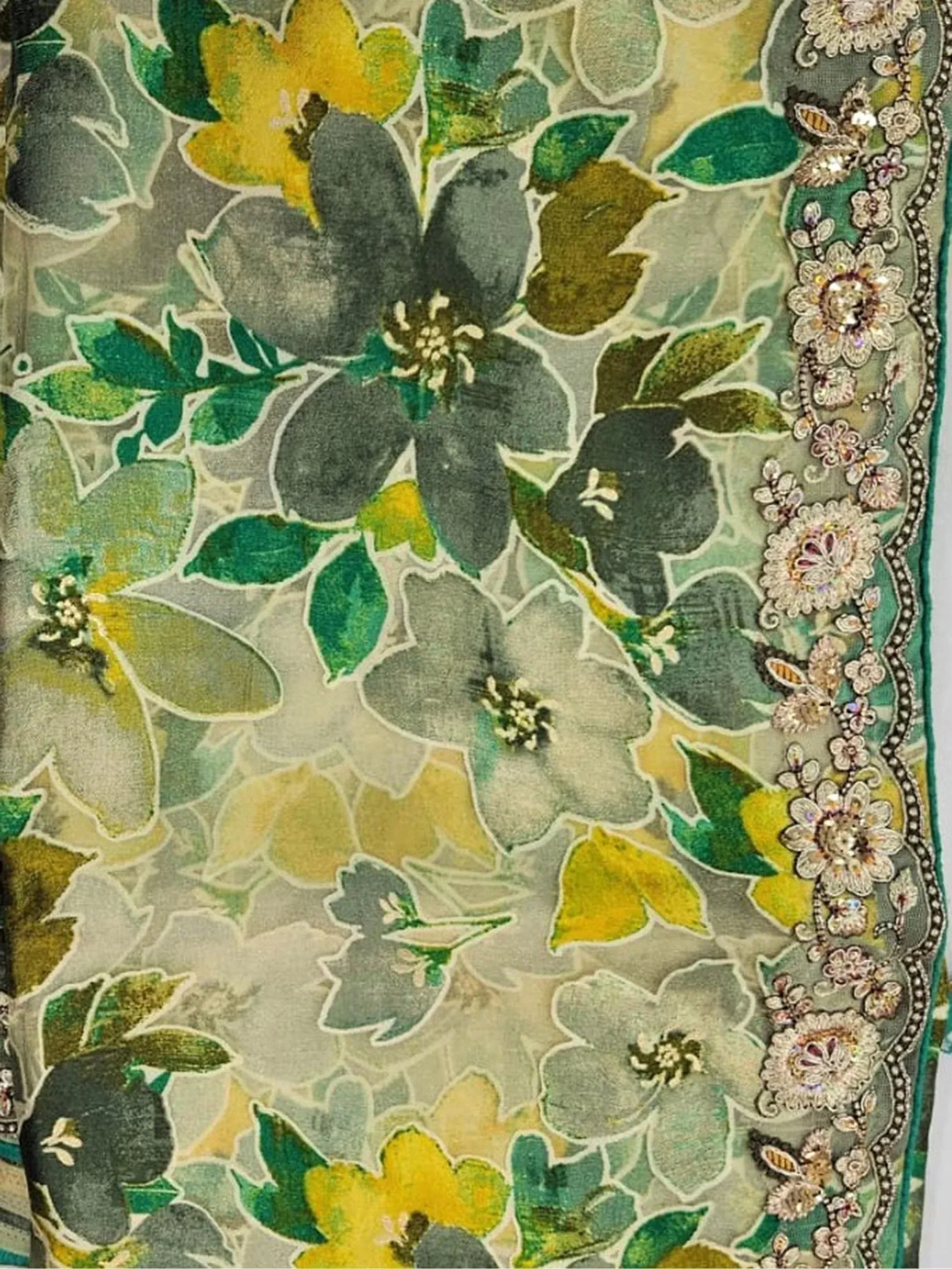 Floral printed ethnic fabric with green, yellow, and grey hues, featuring intricate embroidered border details.