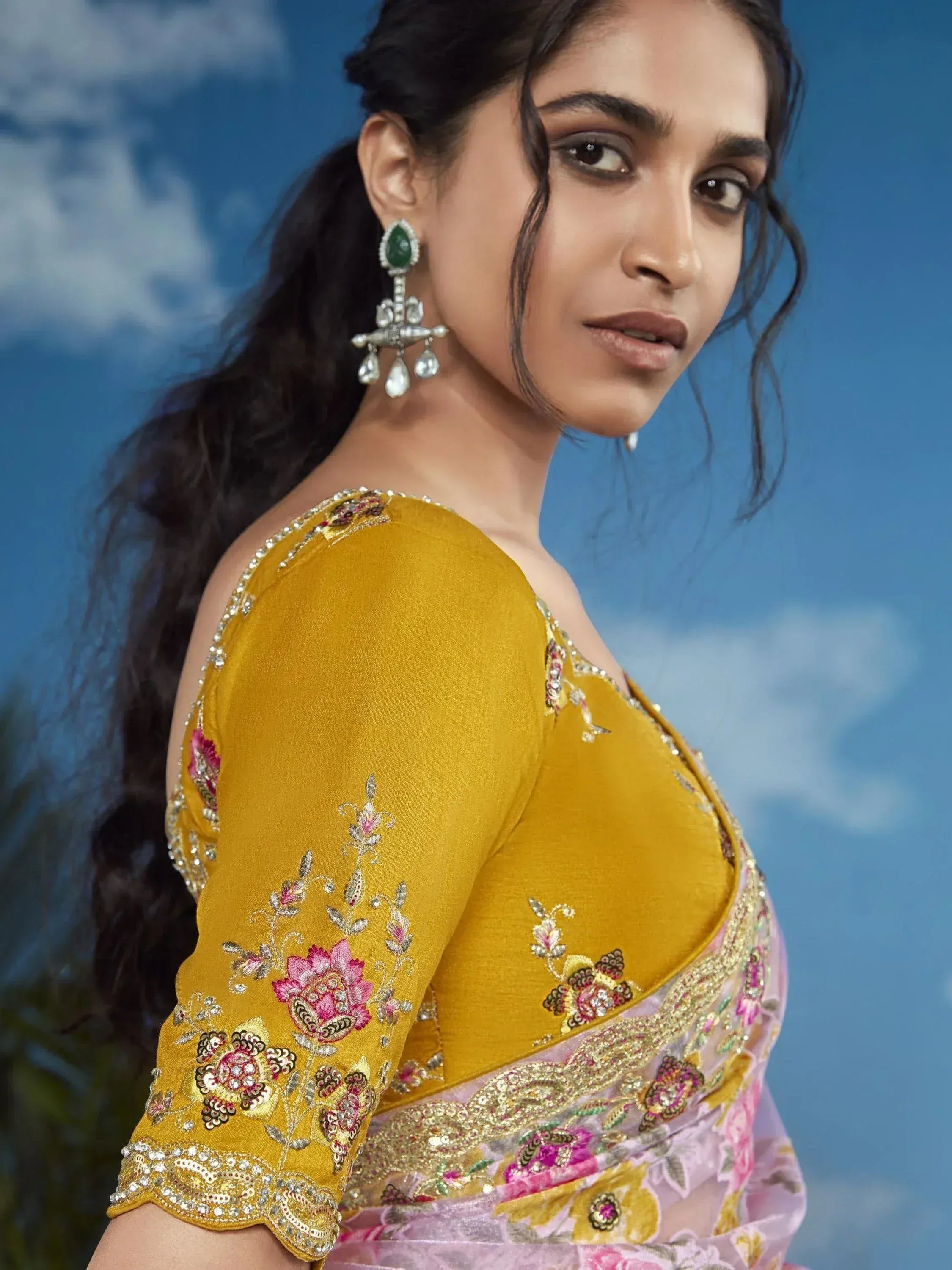 Yellow embroidered designer lehenga choli with floral motifs and green stone earrings
