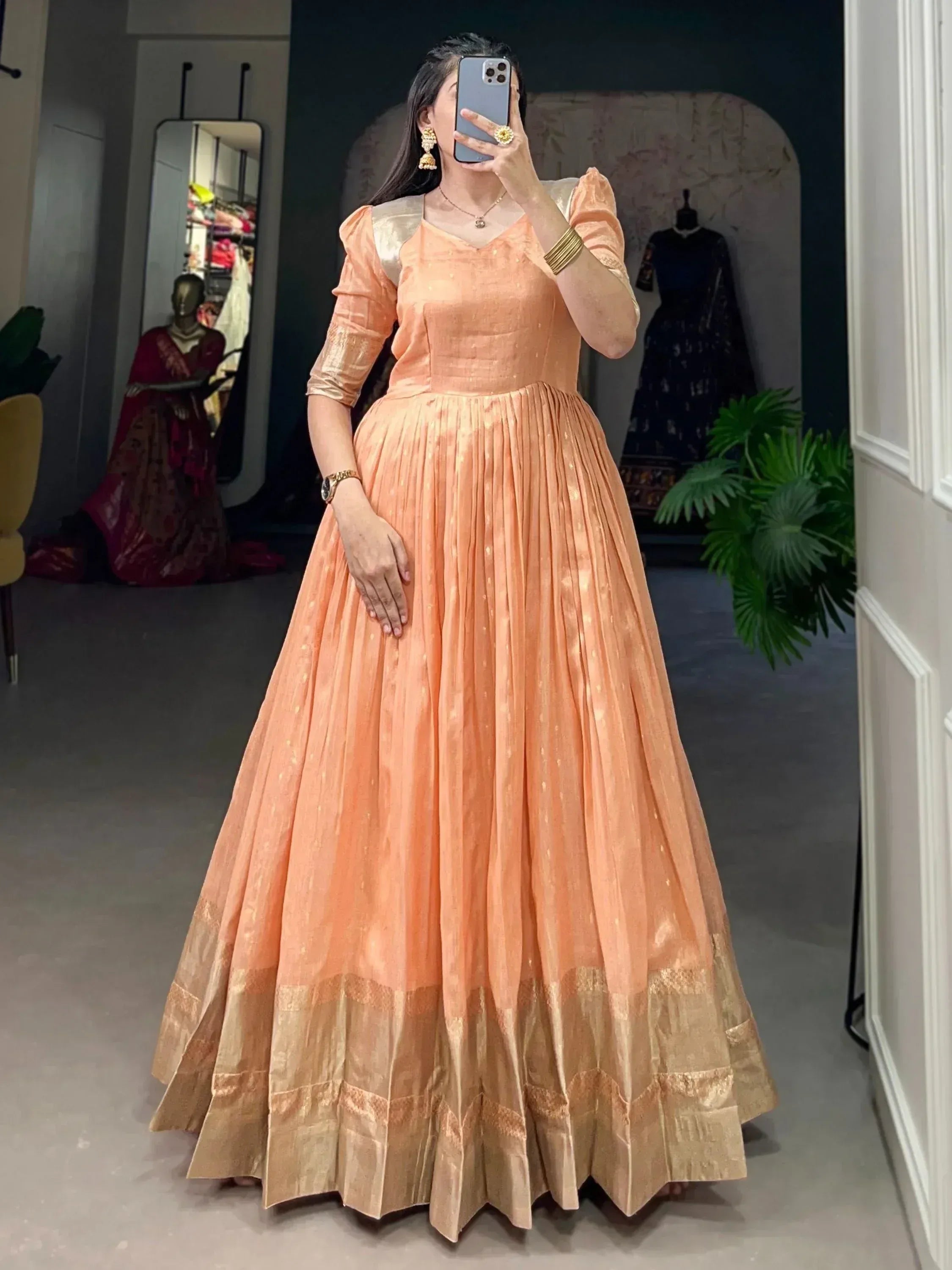 Peach ethnic gown with gold trim, pleated skirt, and puff sleeves for Indian occasions