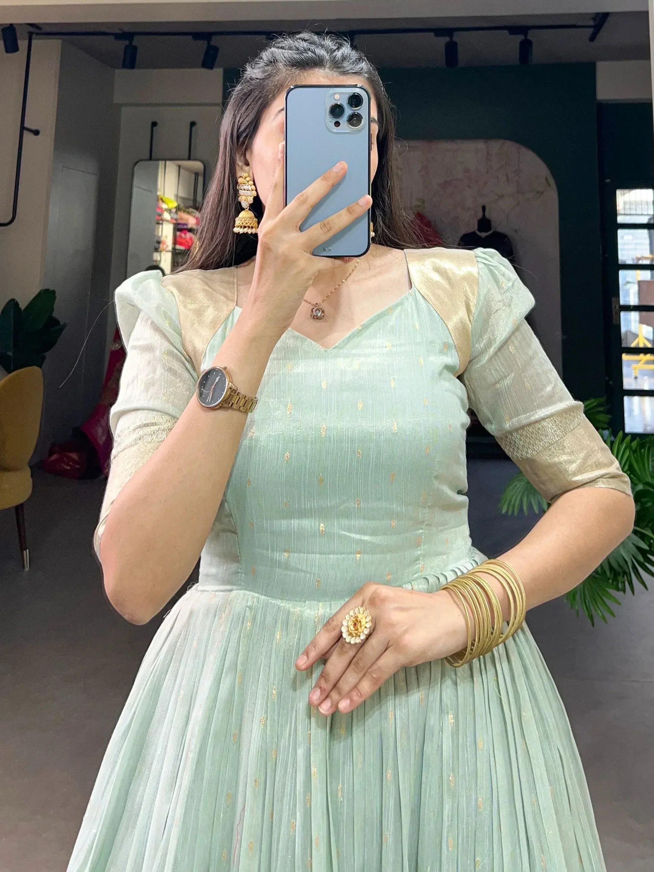 Mint green ethnic gown with gold accents, puff sleeves, and pleated skirt, styled with jhumka earrings and bangles