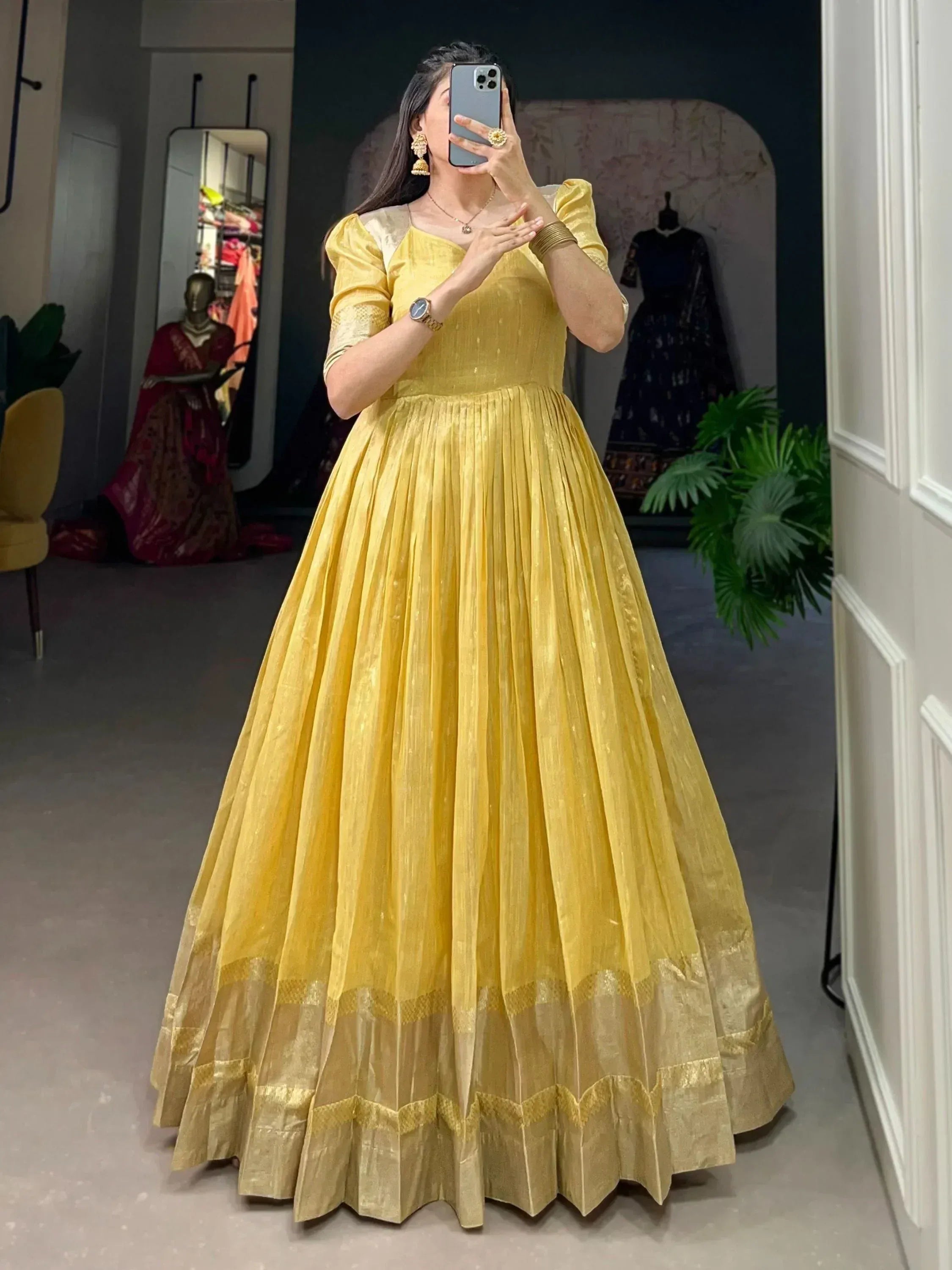 Yellow ethnic gown with pleated skirt and gold trim, perfect for Indian occasions