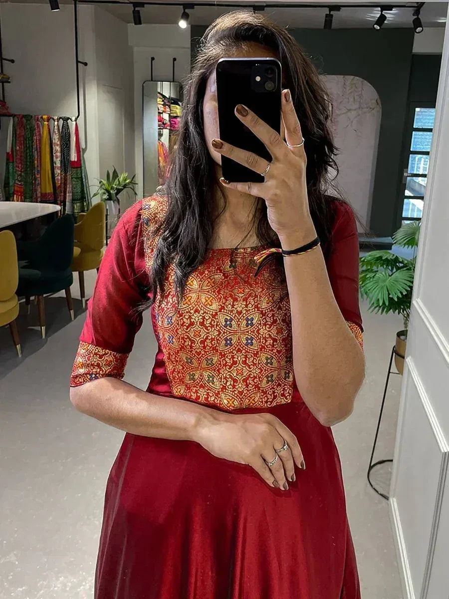 Woman in red ethnic gown with printed bodice, taking mirror selfie in boutique