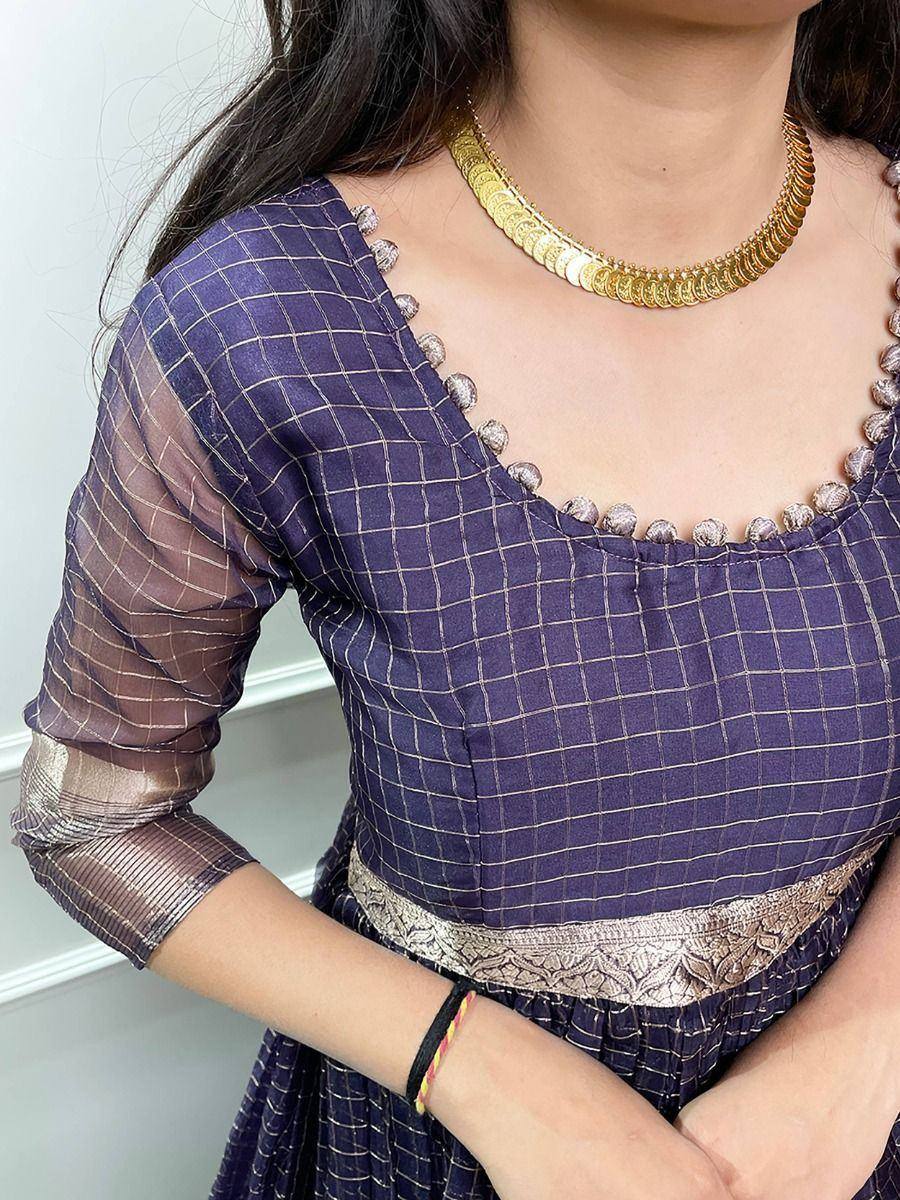 Purple checkered ethnic gown with gold trim and pom-pom detailing, paired with a gold coin necklace.