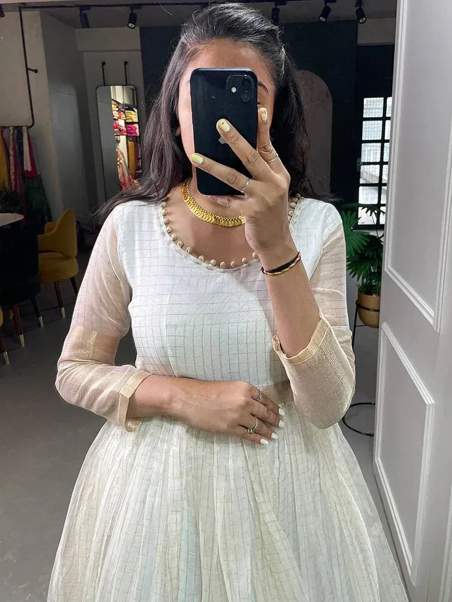 White ethnic gown with pearl neckline, sheer sleeves, and gold jewelry for festive occasions