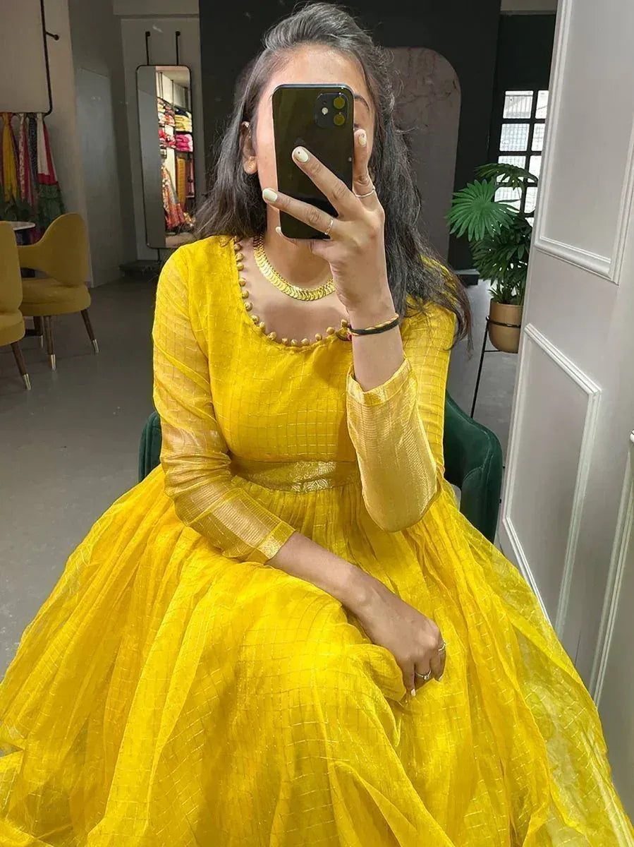 Woman in yellow netted ethnic gown with full sleeves taking mirror selfie in boutique