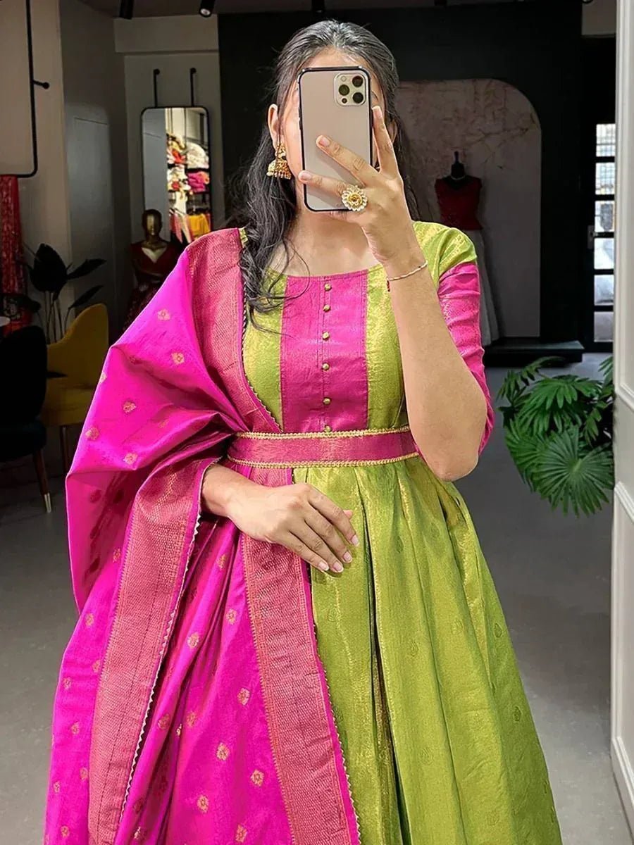 Woman wearing green and pink silk ethnic gown with dupatta and traditional jewelry indoors