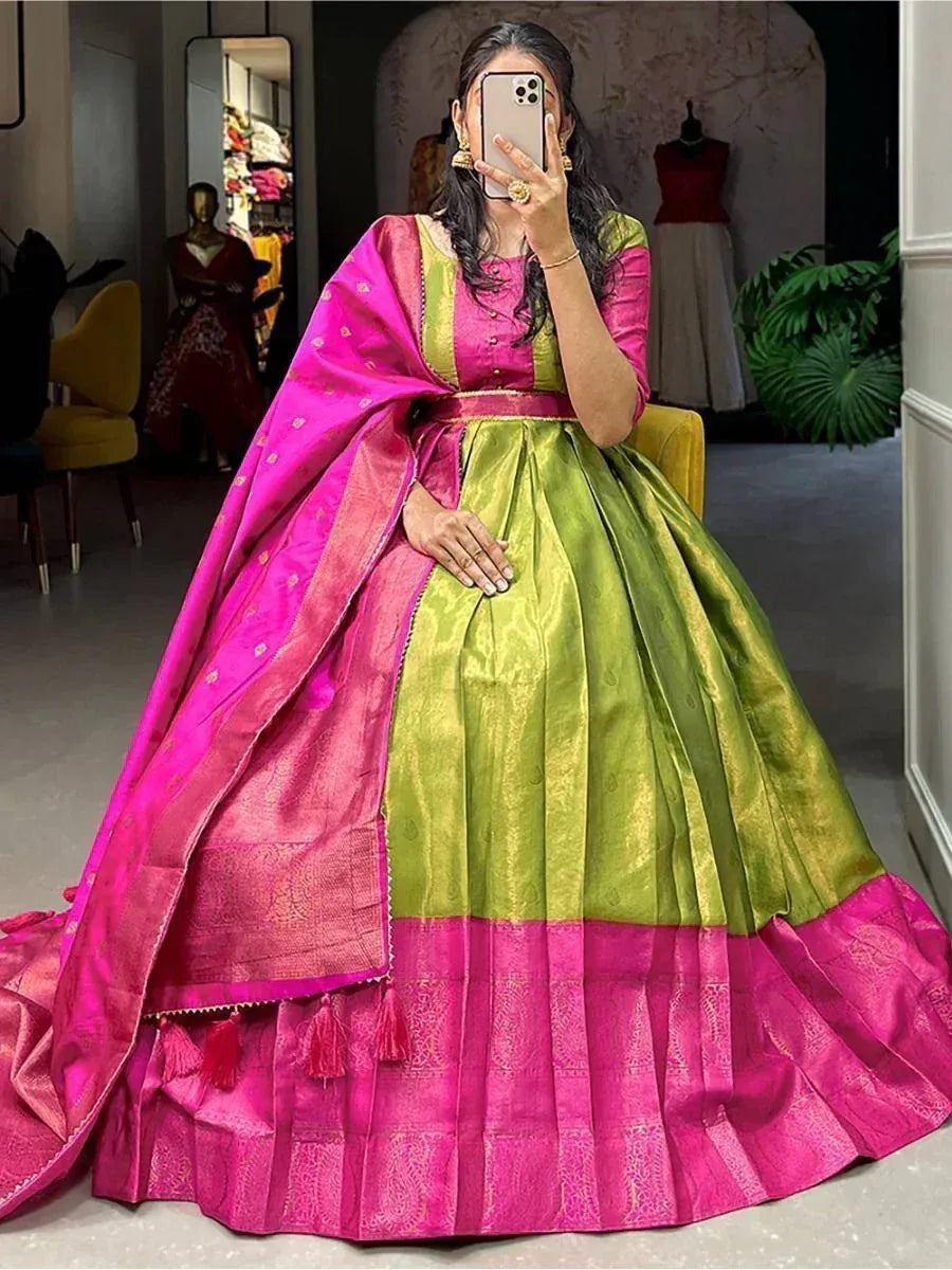Woman wearing a green and pink silk lehenga with dupatta, seated indoors