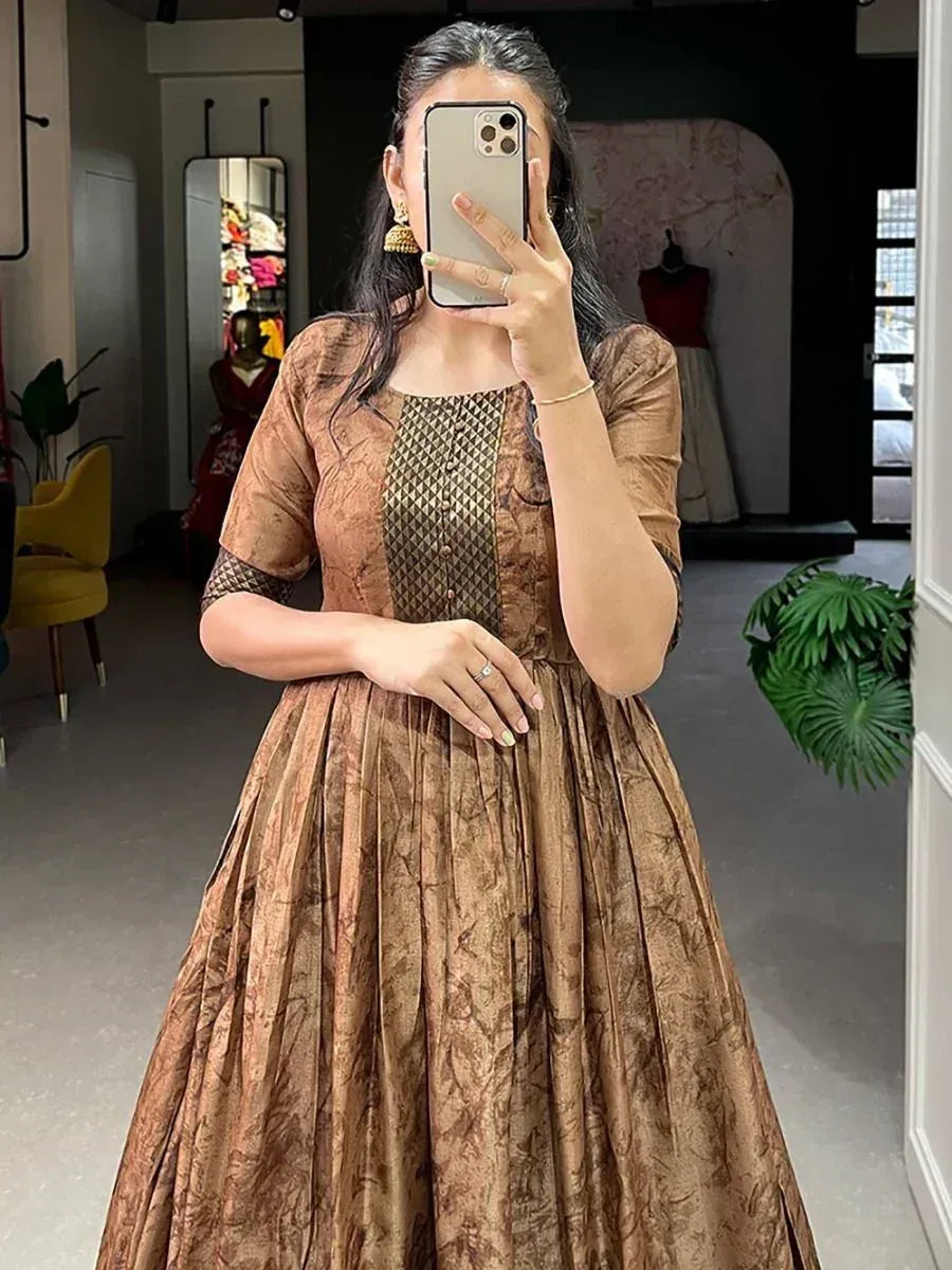 Woman in brown ethnic gown with gold panel, taking mirror selfie in boutique