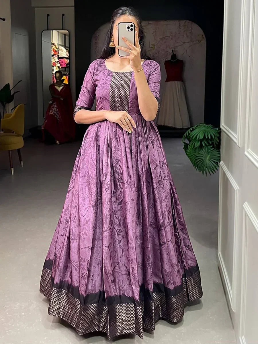 Woman in a purple silk ethnic gown with geometric detailing, posing indoors for a mirror selfie.