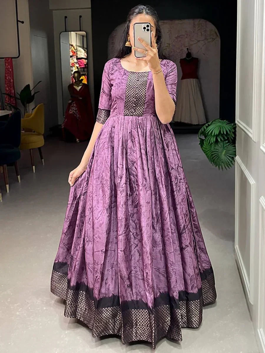 Woman wearing a purple silk ethnic gown with black borders and half sleeves in boutique