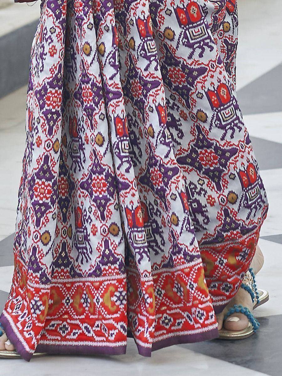 Vibrant purple and red printed ethnic skirt with intricate patterns, paired with blue sandals.