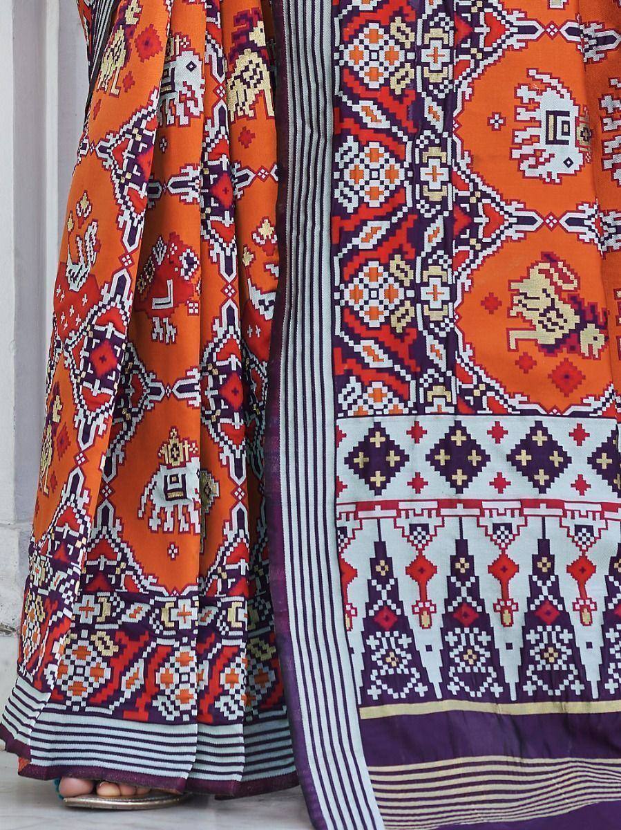 Vibrant orange and purple ethnic lehenga with intricate geometric and elephant motifs, perfect for festive occasions.