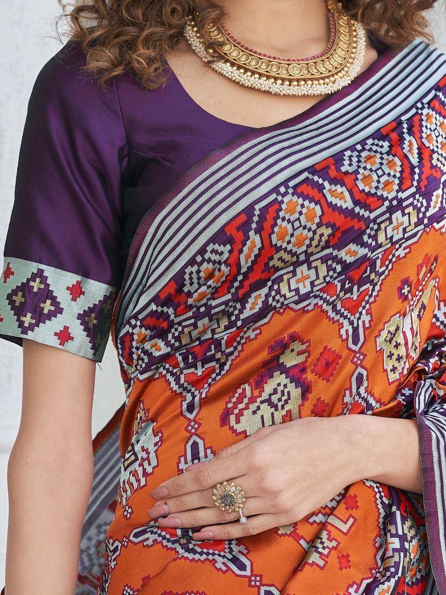 Vibrant orange and purple ethnic saree with geometric print, paired with matching blouse and gold jewelry