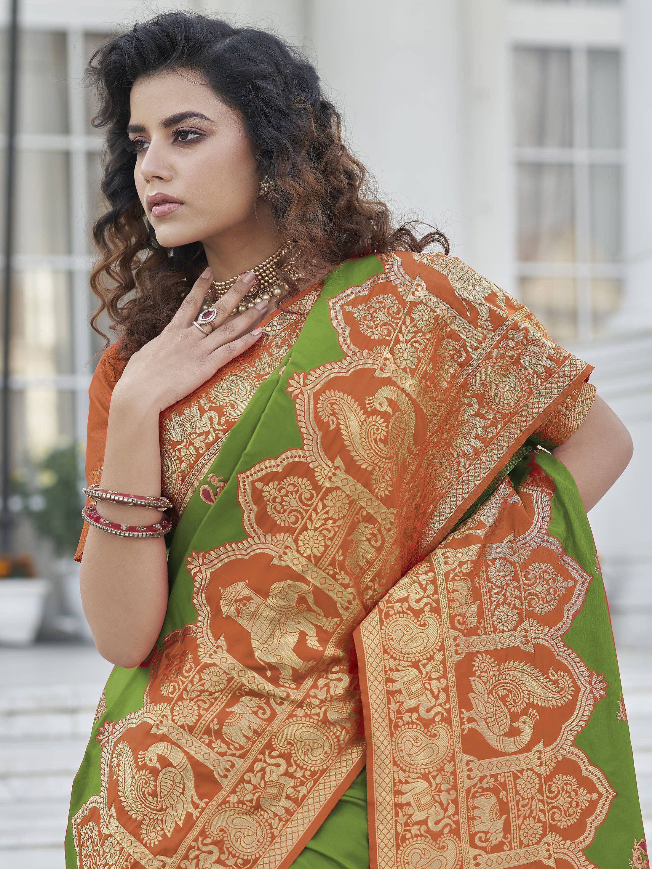 Woman in orange and green designer saree with gold paisley and elephant motifs, ethnic wear