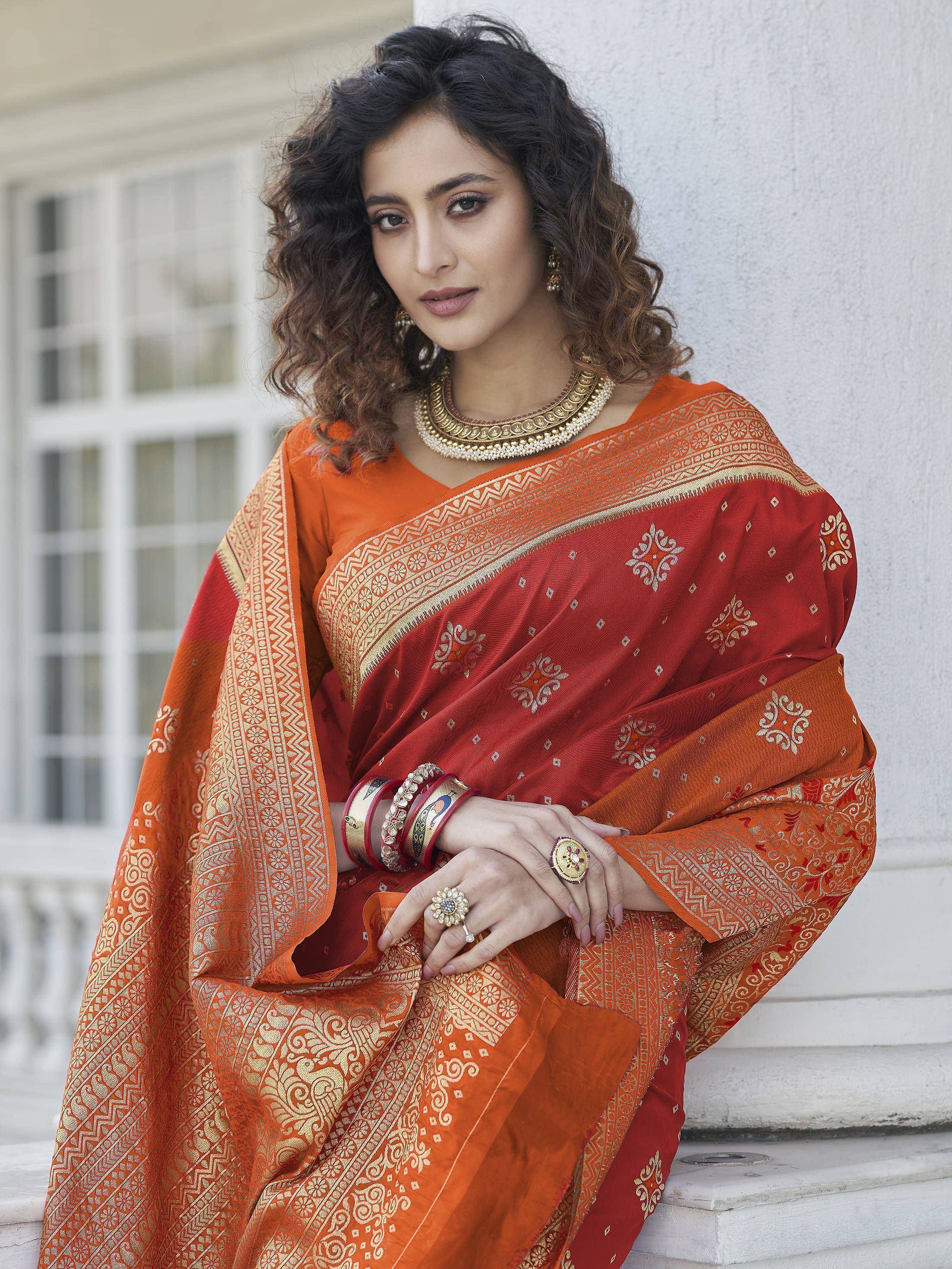 Woman in elegant red and orange ethnic saree with gold embroidery, traditional jewelry, perfect for festive occasions.