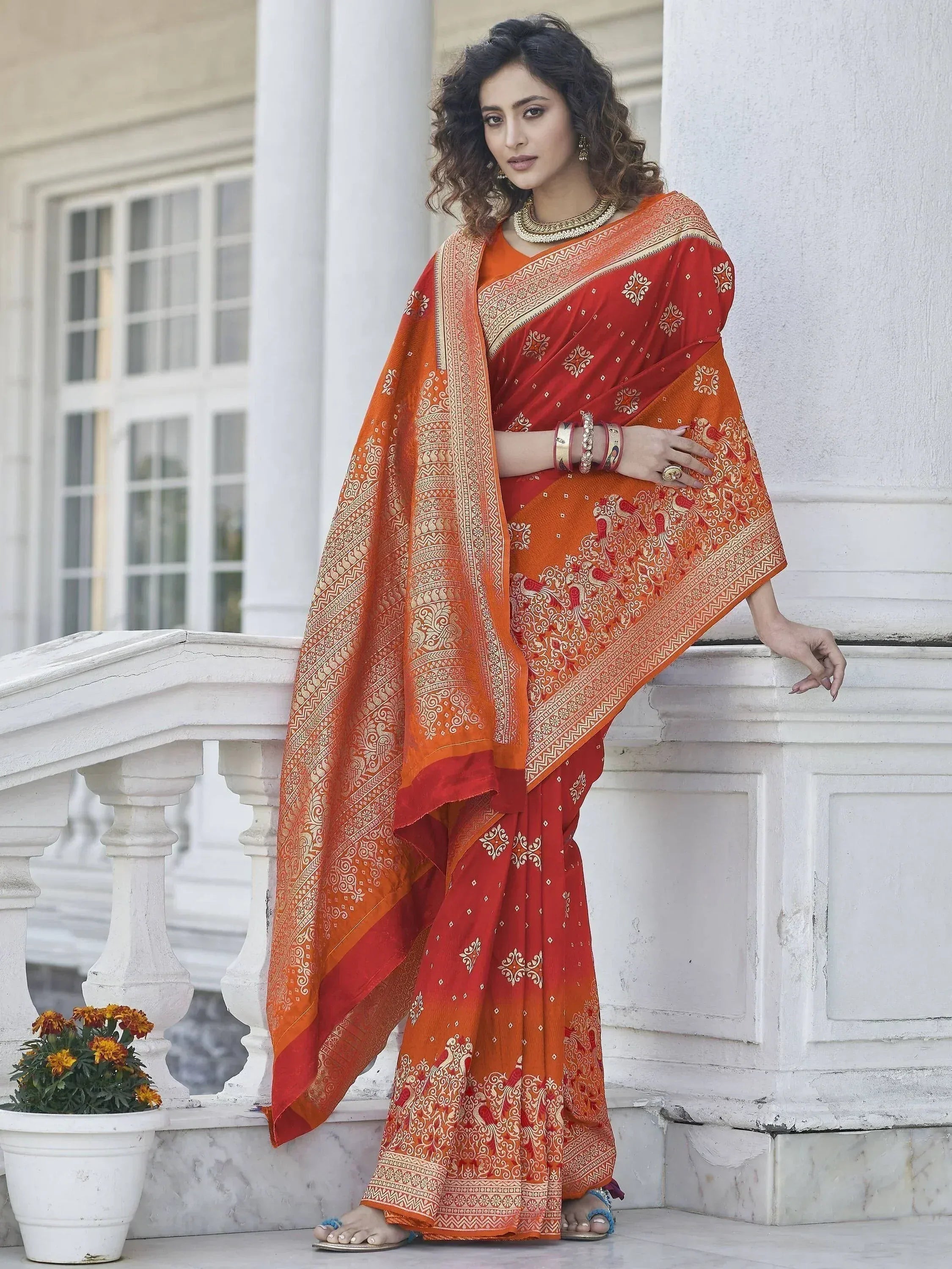 Elegant red and orange ethnic saree with intricate gold patterns, perfect for traditional occasions.
