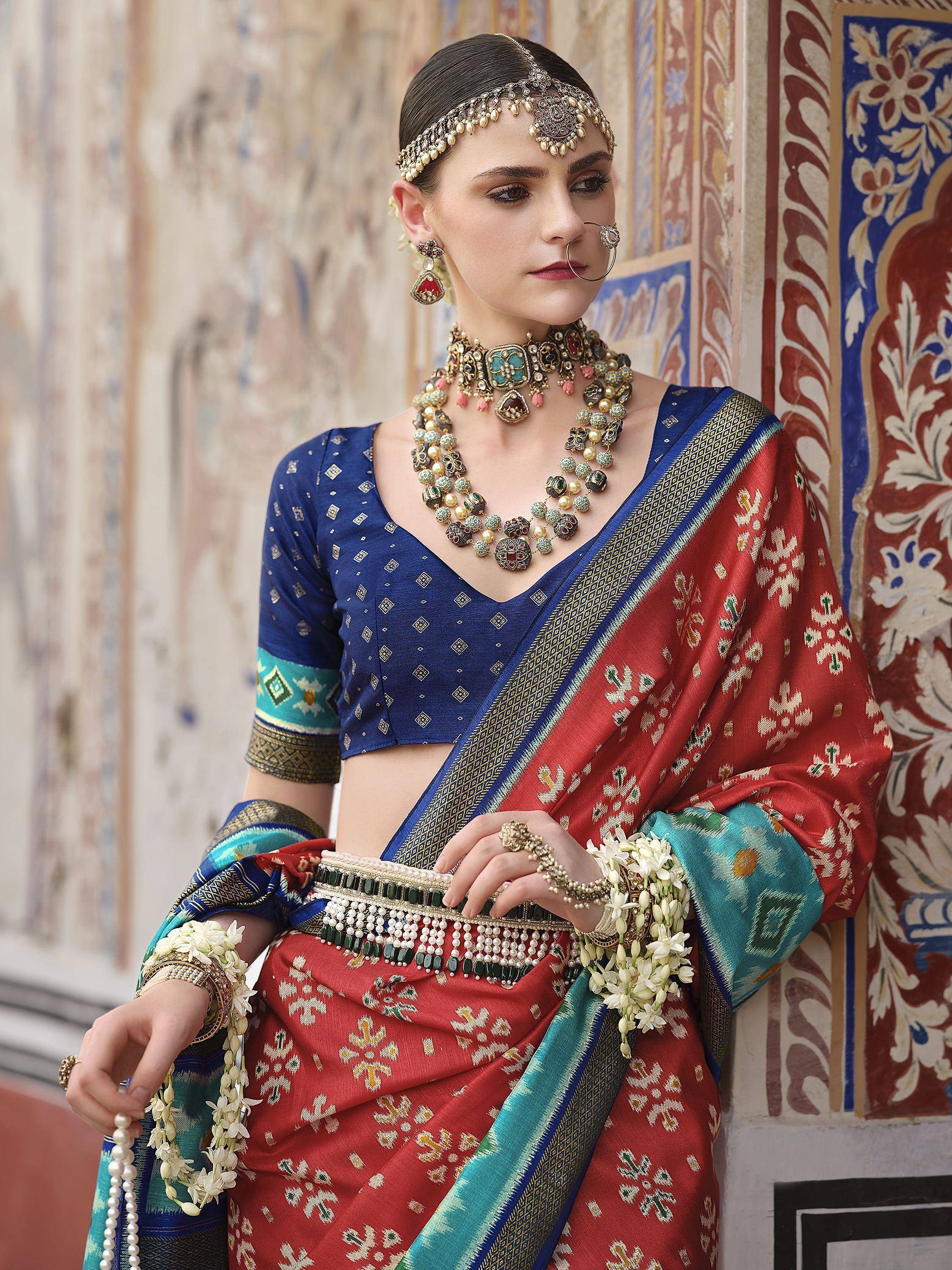 Woman in red and blue ethnic saree with gold jewelry, traditional Indian attire for festive occasions