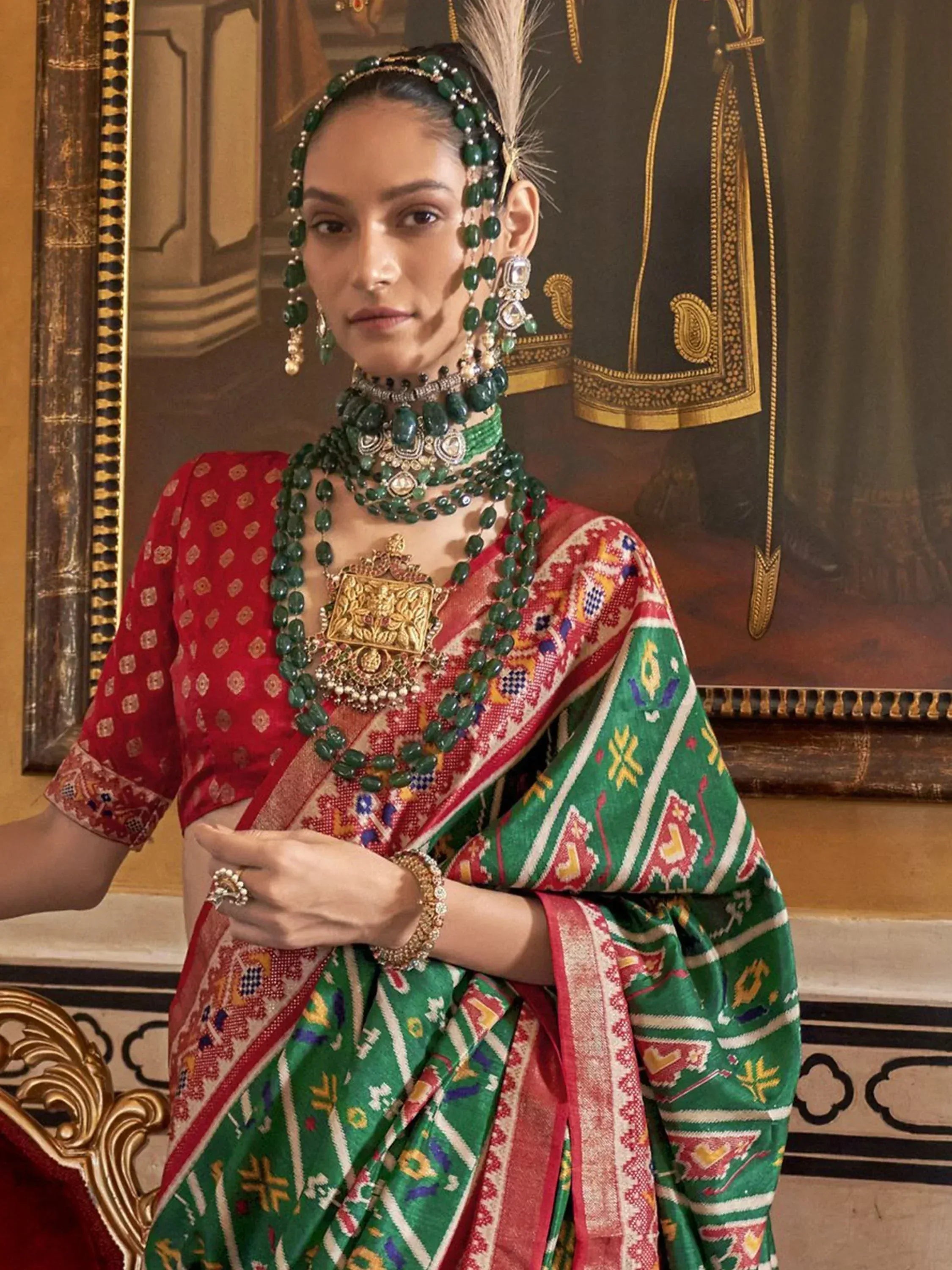 Woman in vibrant red and green ethnic saree with intricate patterns and traditional jewelry, perfect for festive occasions.