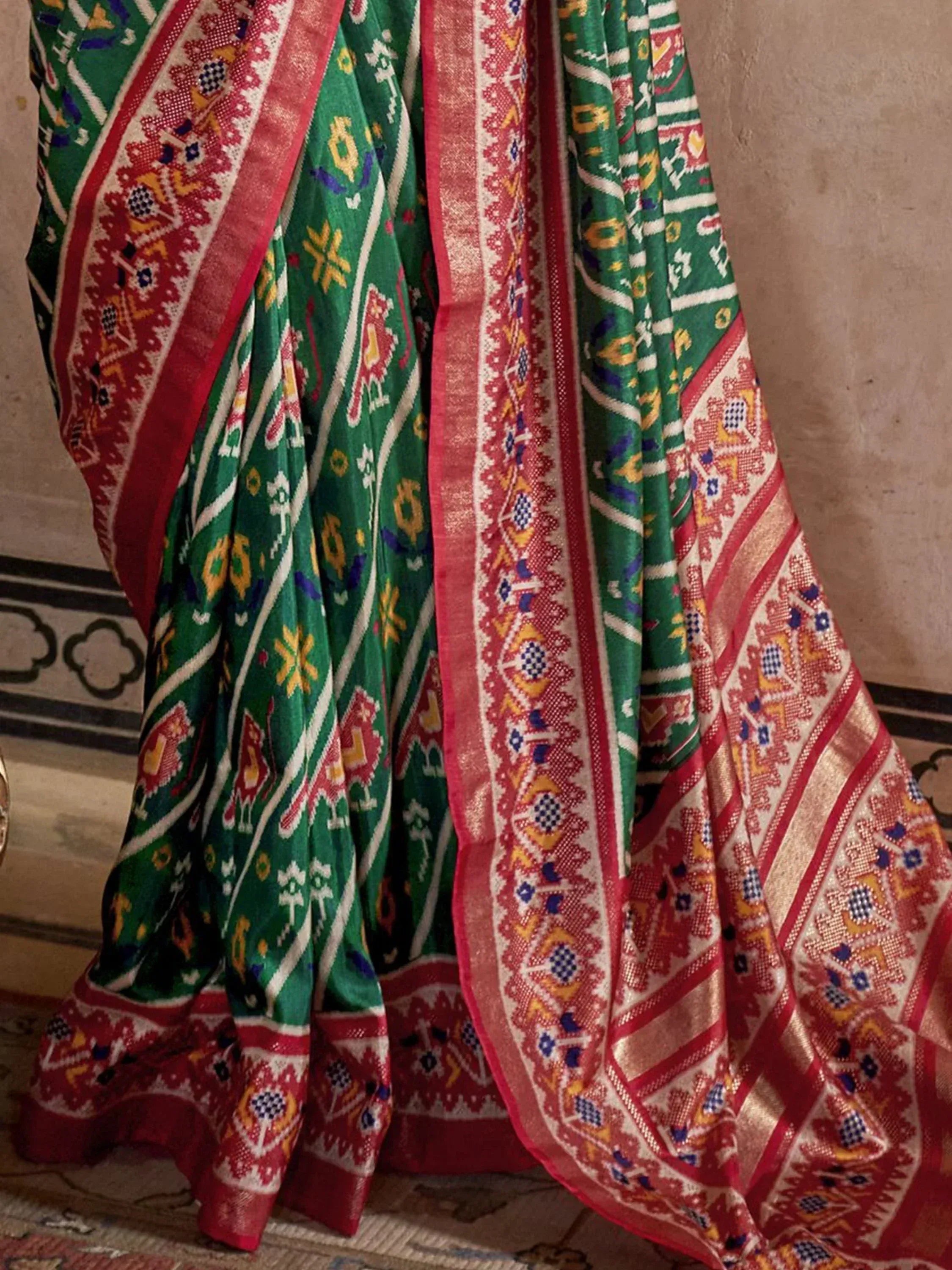 Green and red ethnic saree with intricate geometric and floral patterns, perfect for traditional Indian wear.